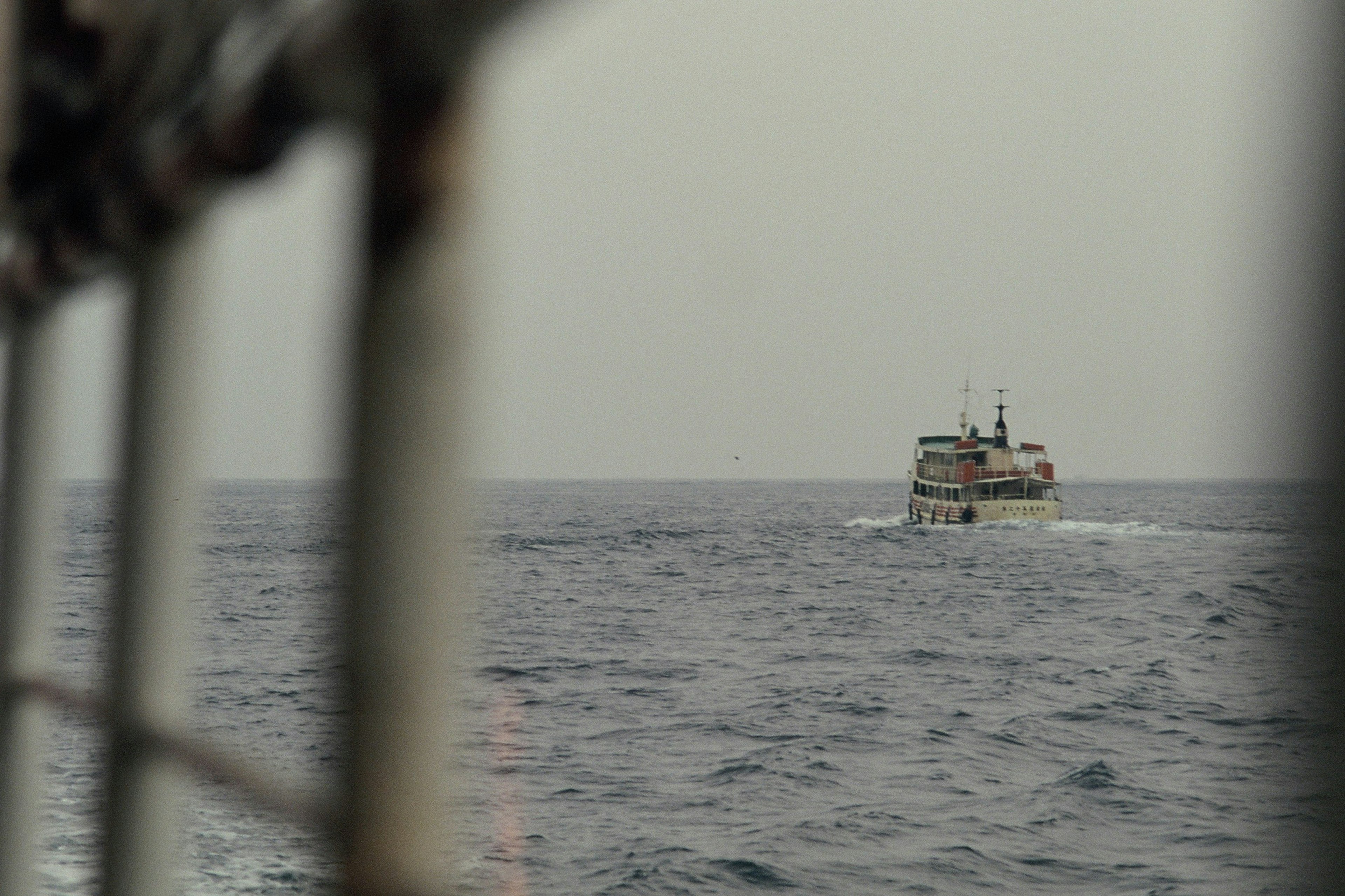 Sebuah perahu berlayar di laut dengan permukaan tenang di latar belakang