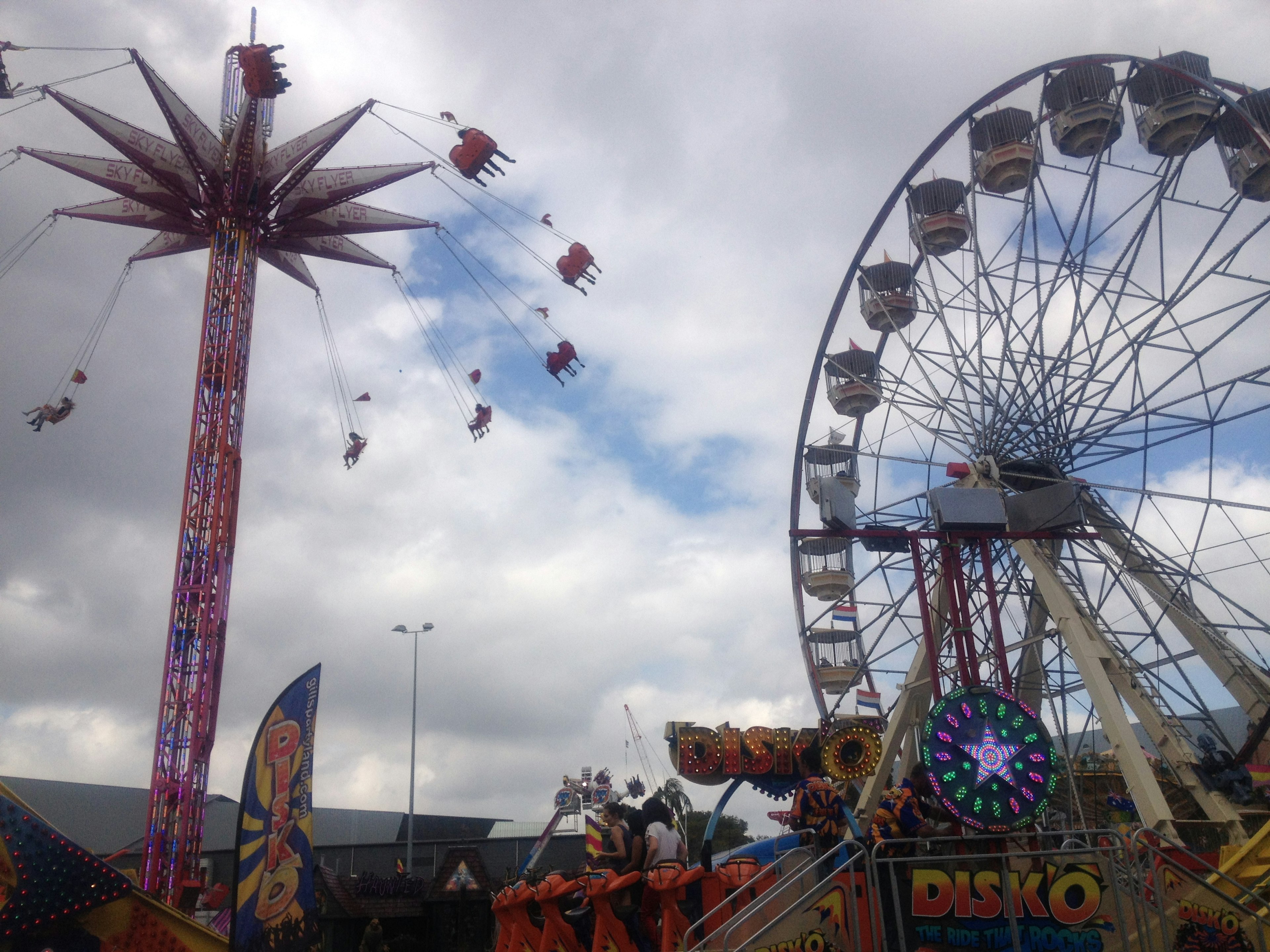 Vista de una noria y un juego de sillas voladoras en un parque de atracciones