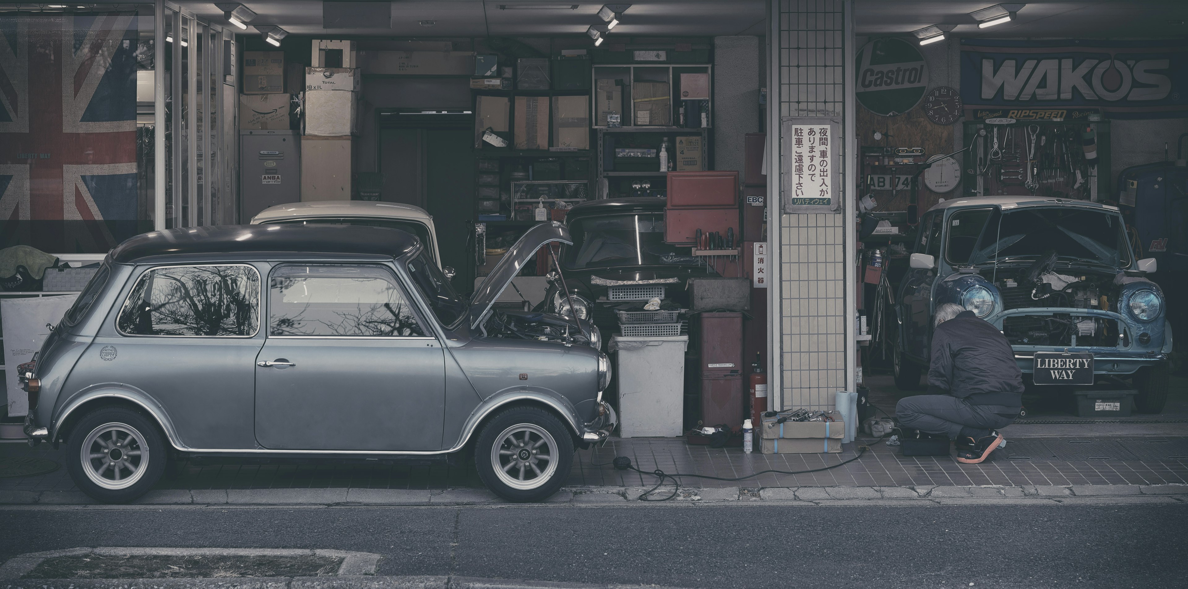 Une voiture vintage devant un garage avec un mécanicien au travail