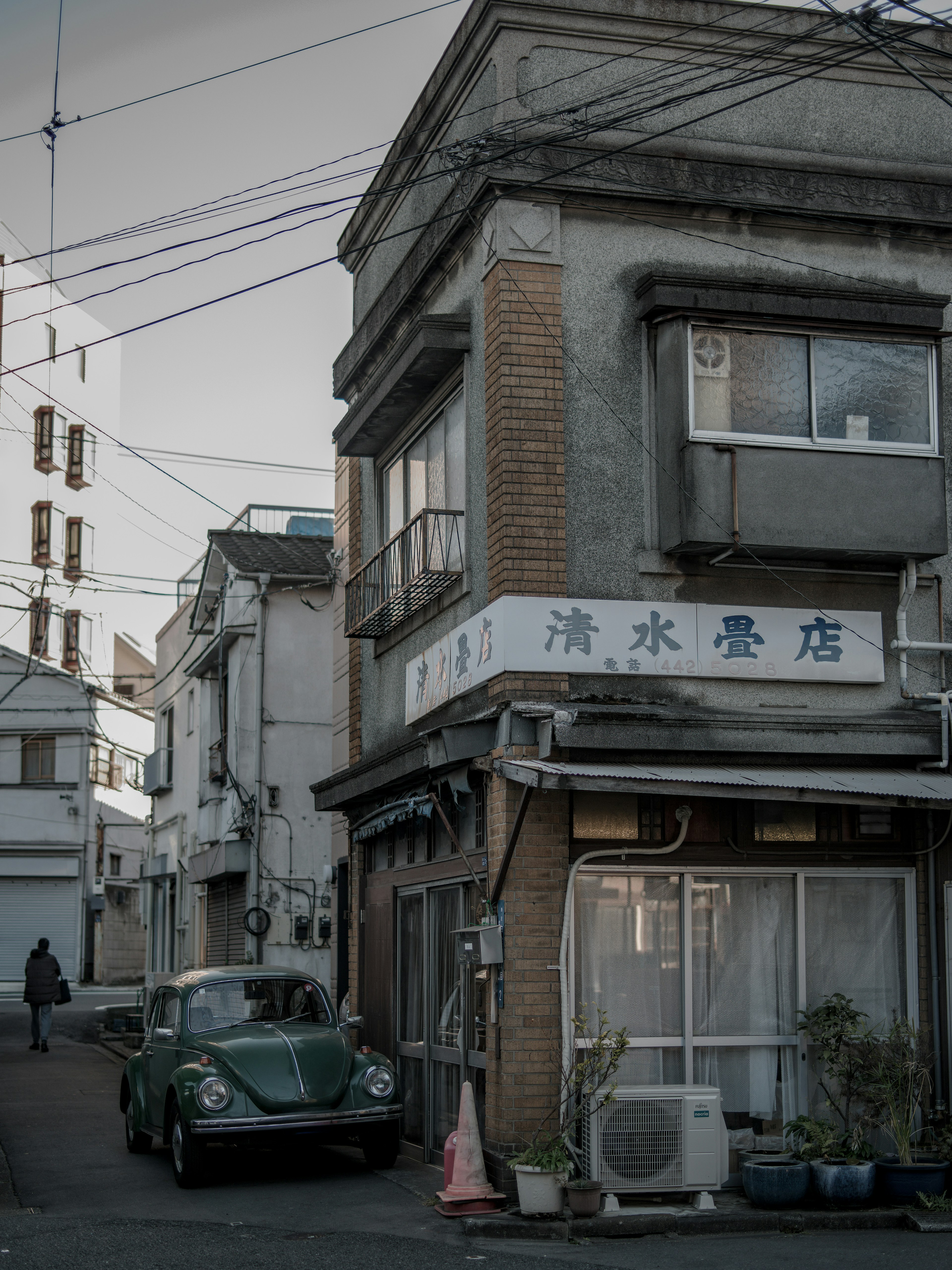 Narrow street scene featuring an old building and a green car