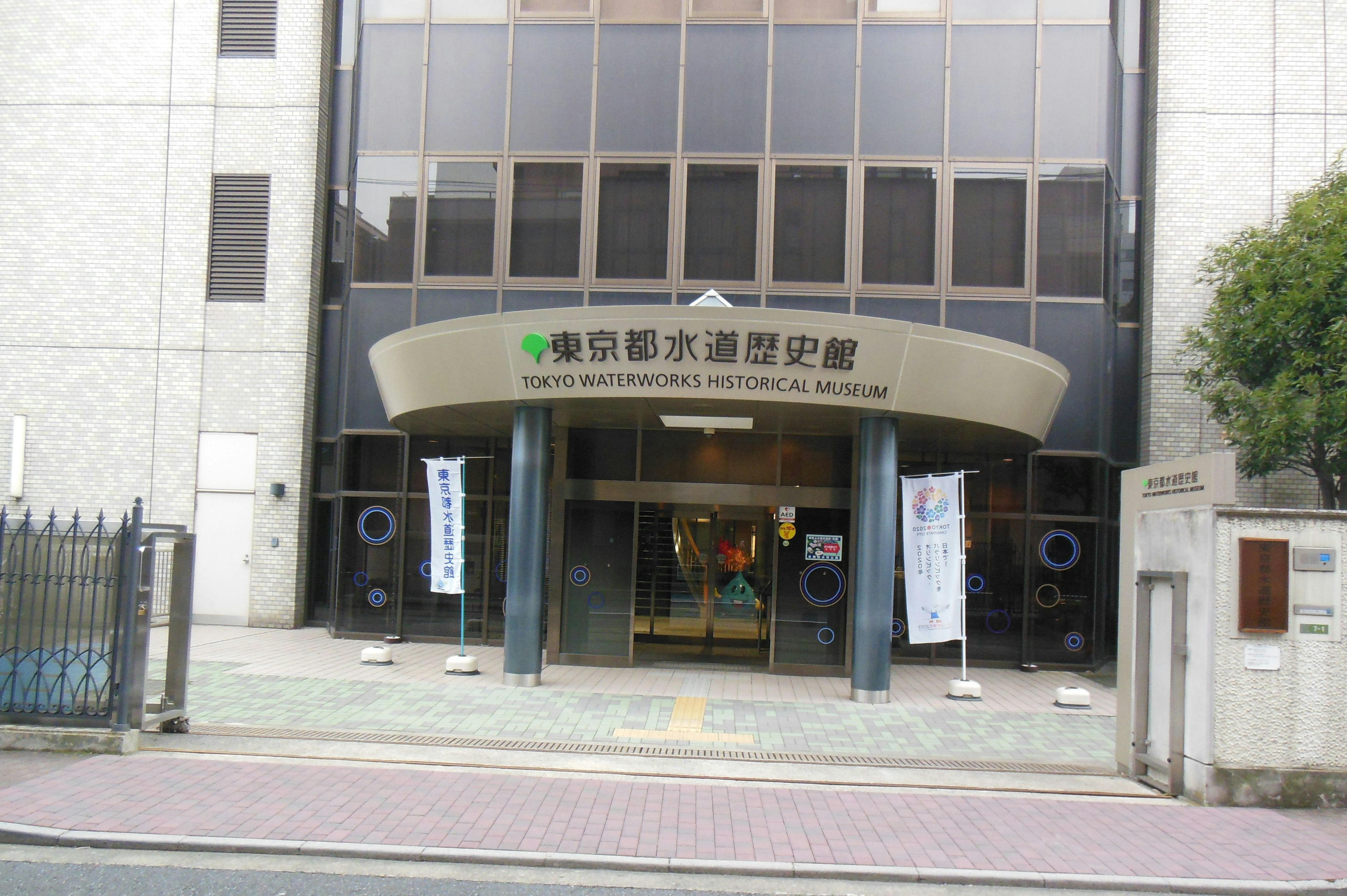 The entrance of a building features a large sign with banners displayed around it