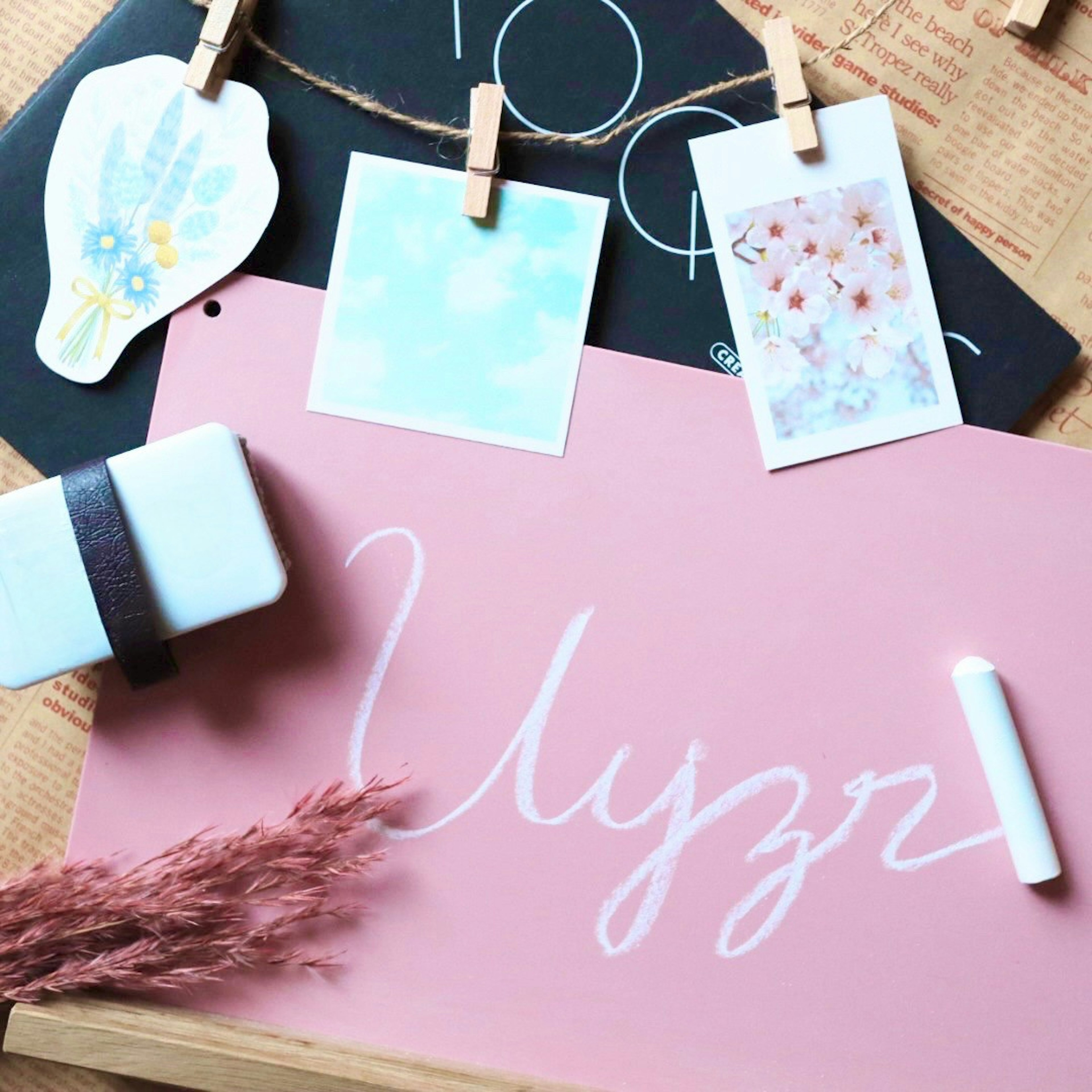 A workspace featuring a pink board with handwritten text in white chalk and clipped photos above