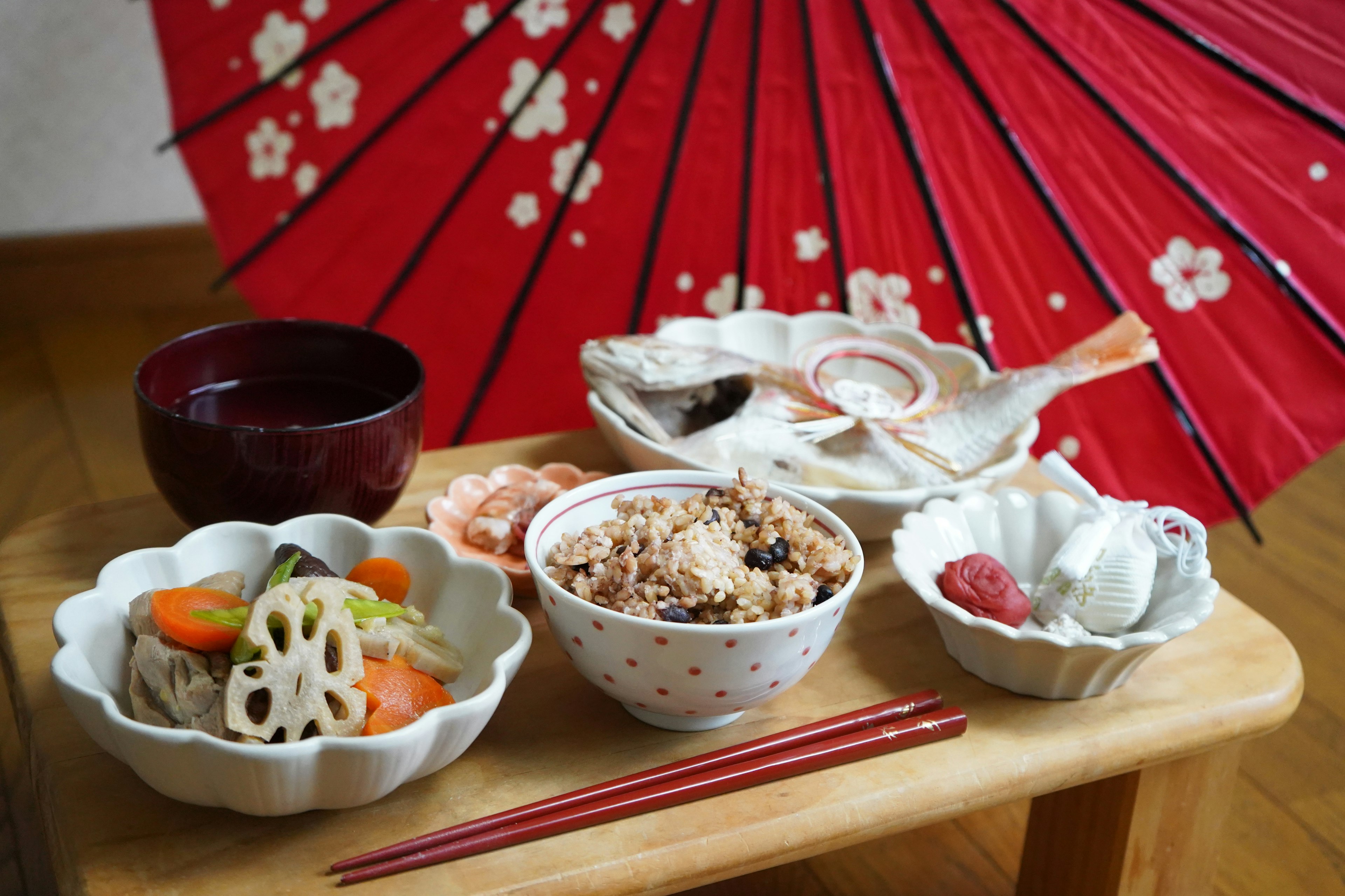 Pengaturan meja dengan masakan Jepang dan latar belakang payung merah