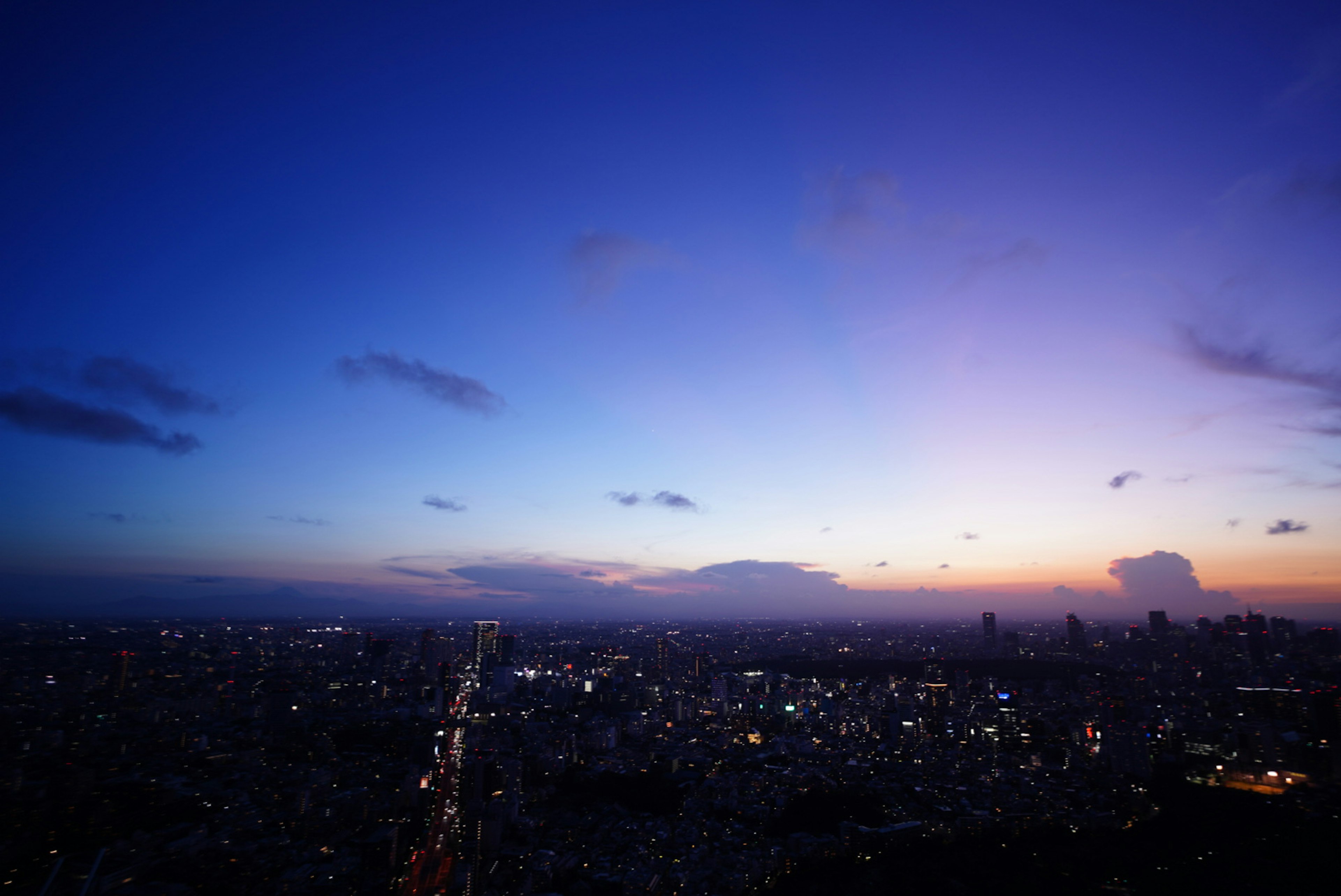 Pemandangan panorama kota di senja langit biru dan ungu dengan lampu kota yang berkilau