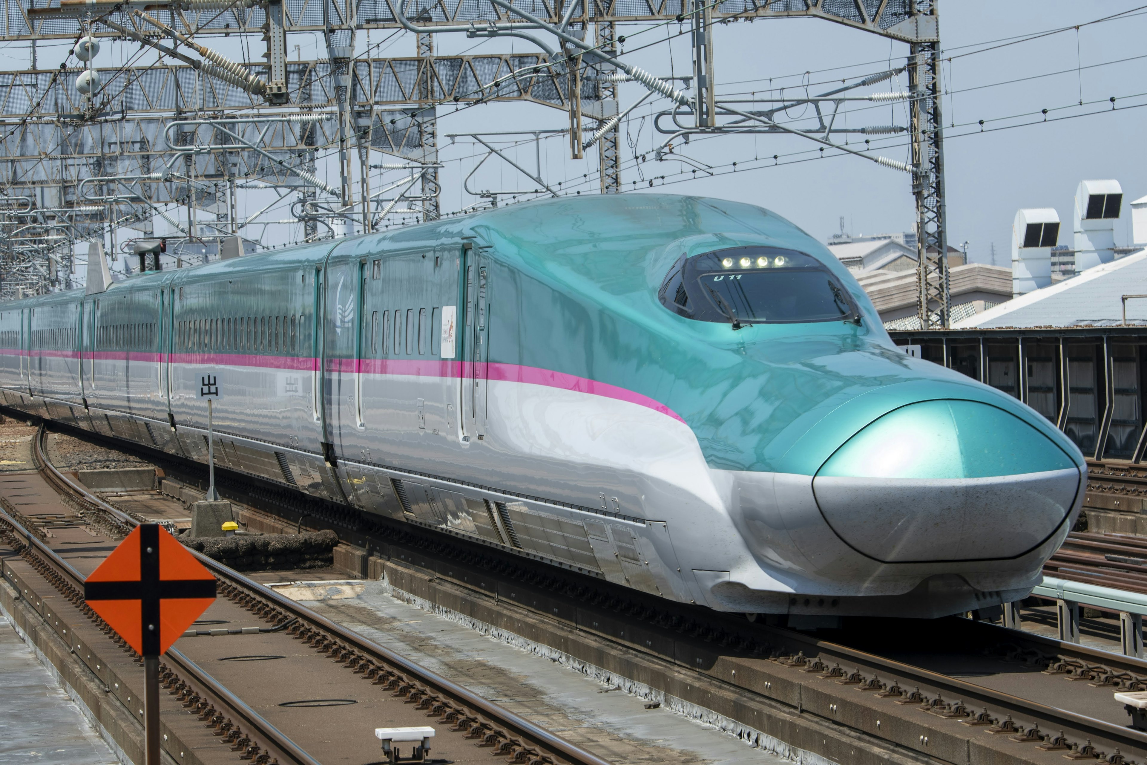 Shinkansen-Zug in teal und silber an einem Bahnhof