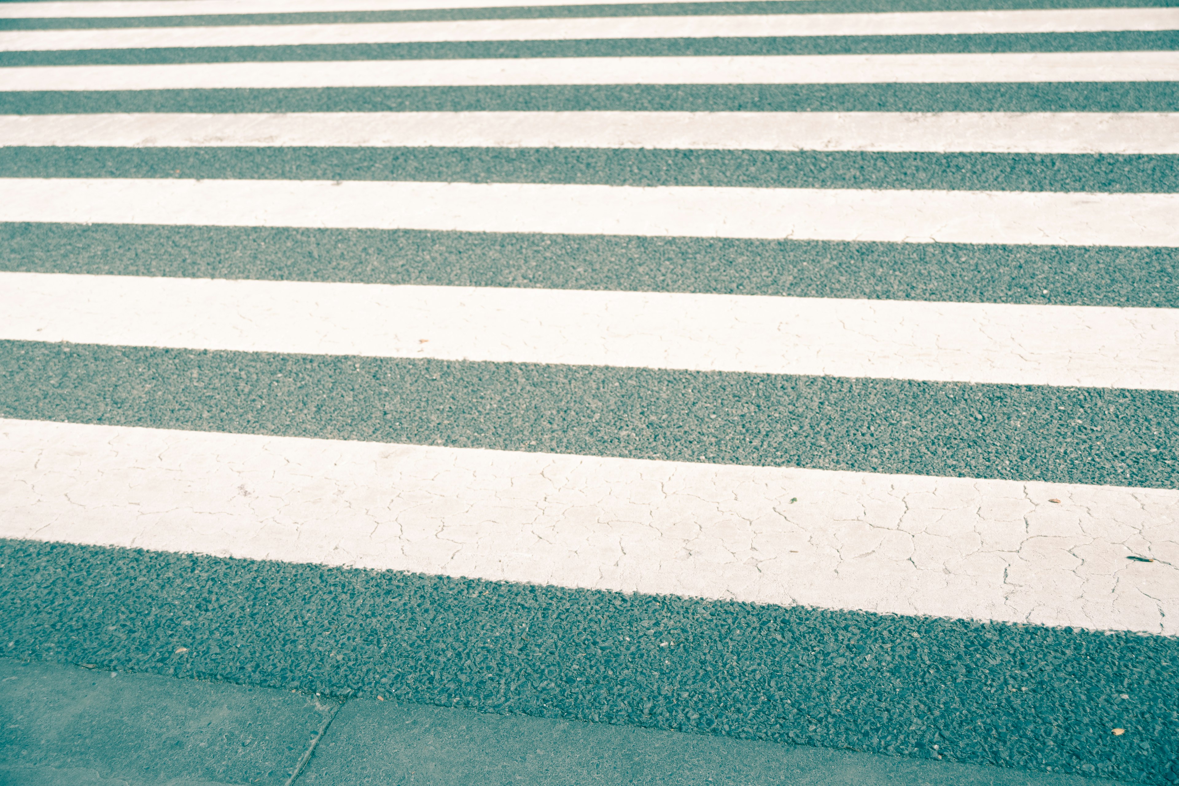 A crosswalk with alternating blue and white stripes