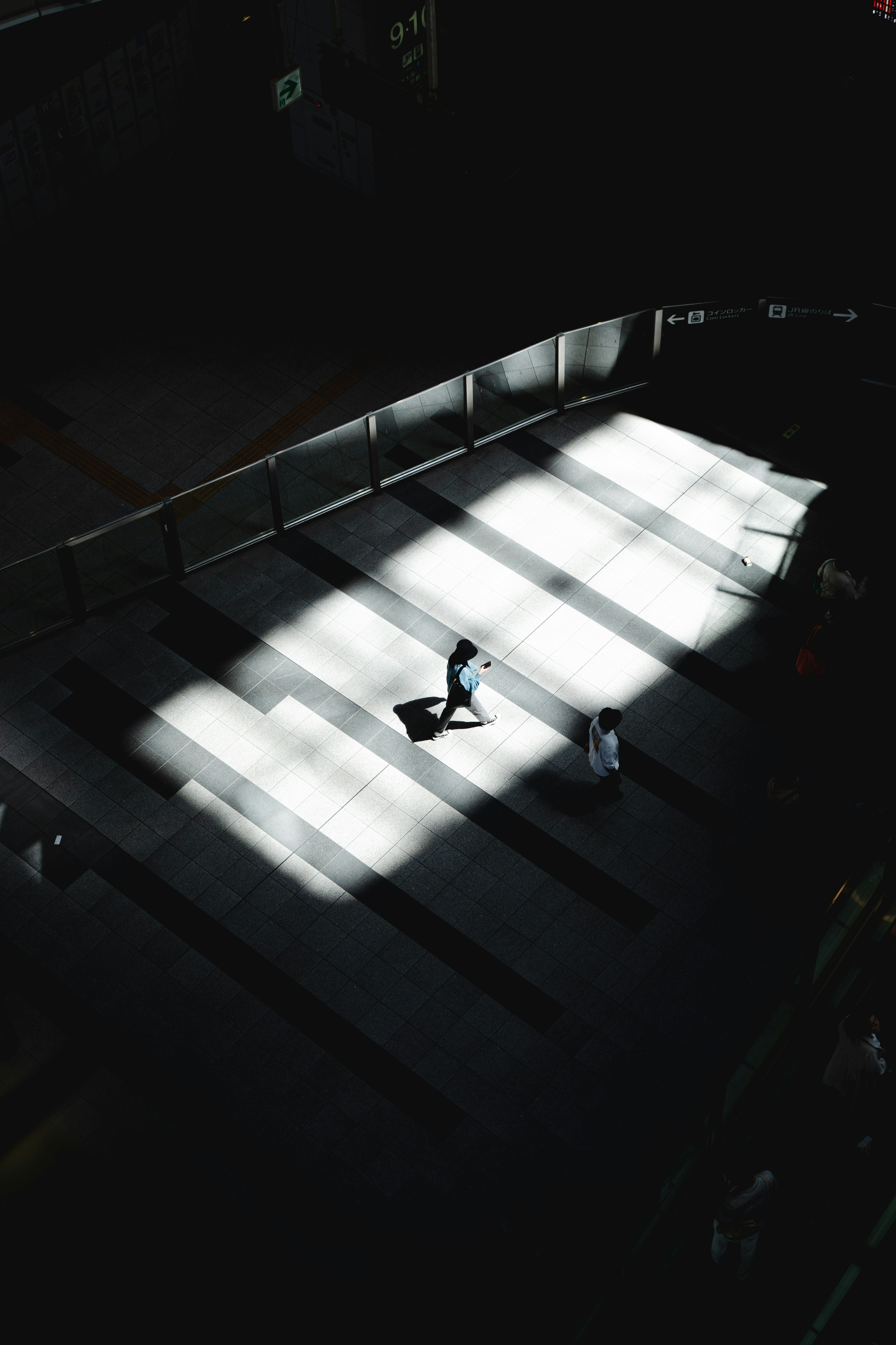 Two figures walking in a space illuminated by bright light