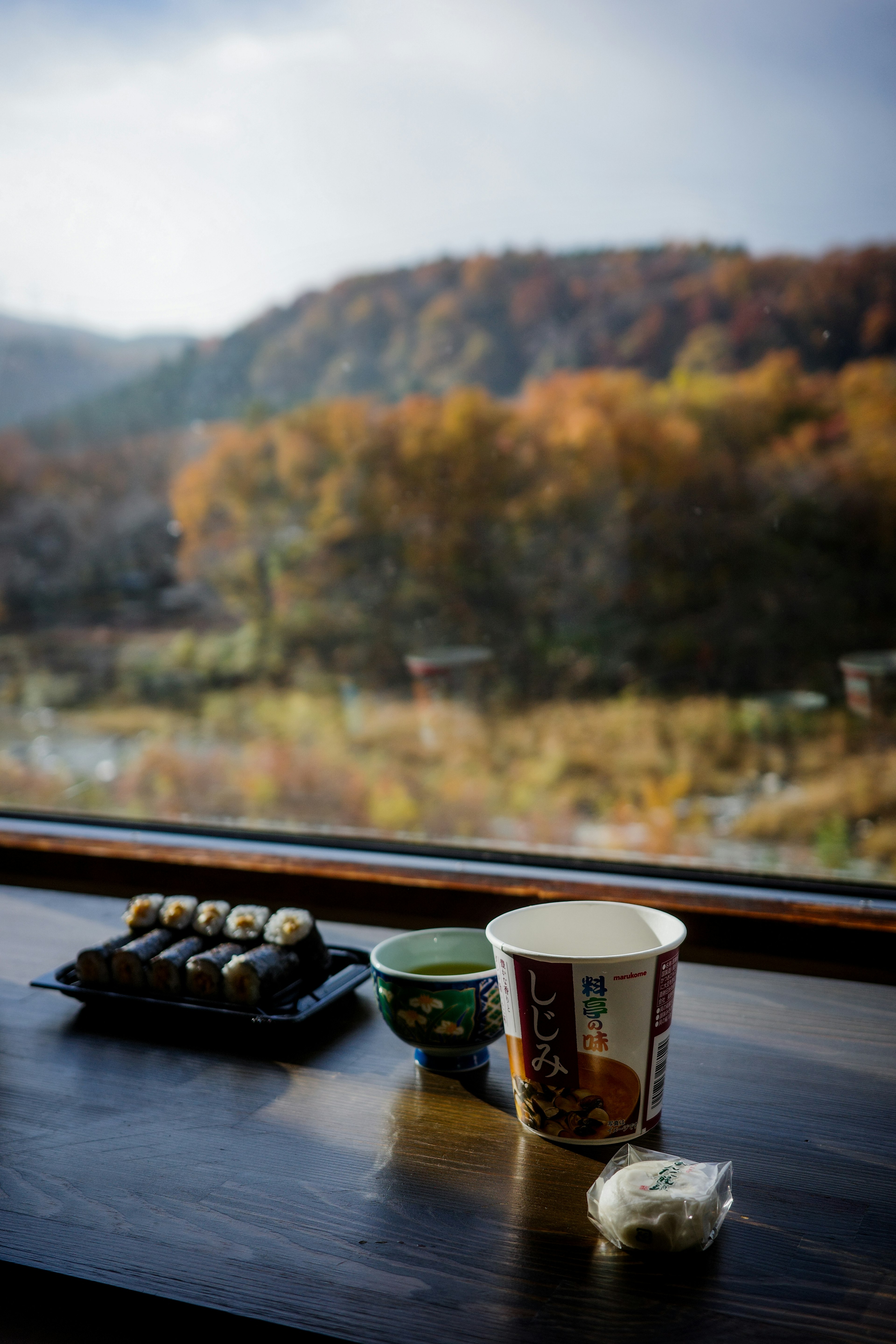 Ensemble de sushi et de thé sur un rebord de fenêtre avec un paysage automnal