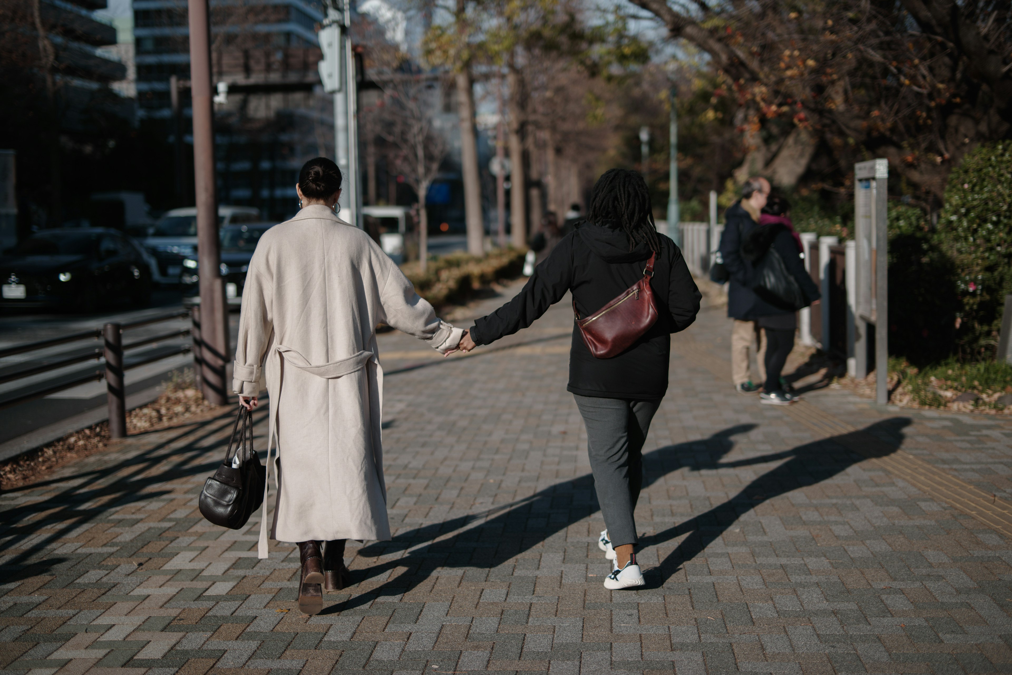 두 사람이 도시 보도에서 손을 잡고 걷고 있다