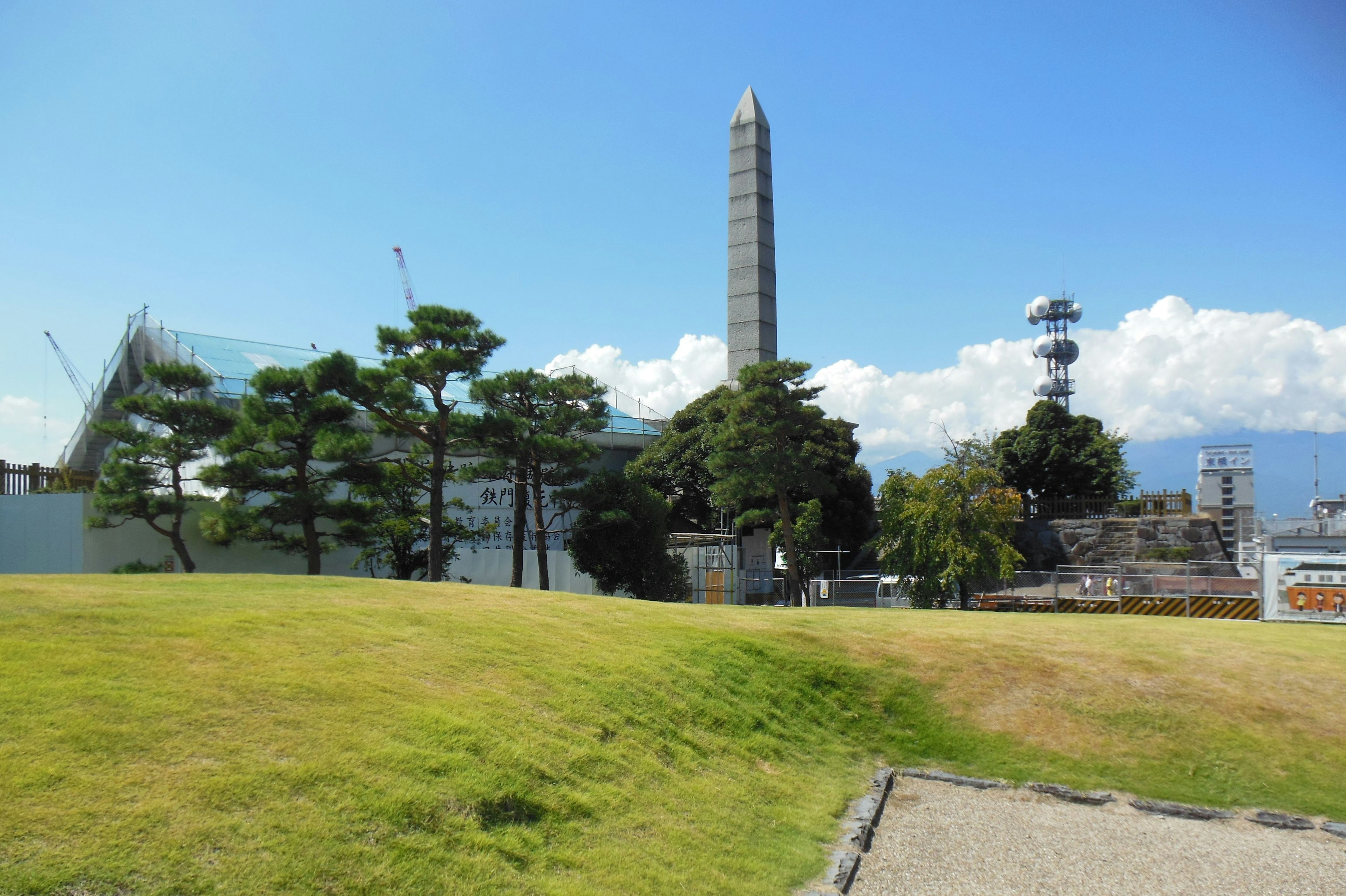 ทิวทัศน์ที่มีหญ้าสีเขียวและเสาอ obelisk สูงในพื้นหลัง