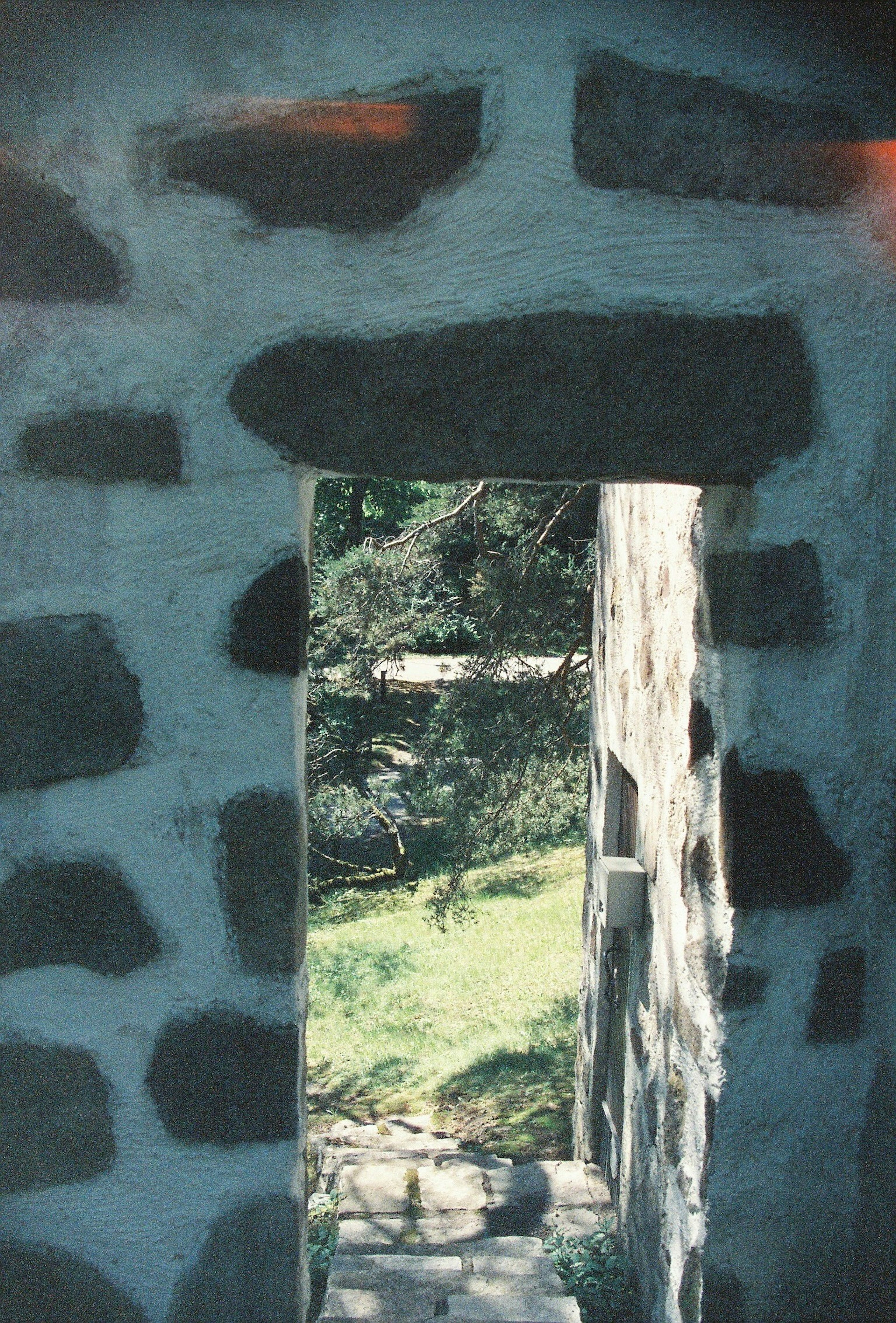 Vue à travers une ouverture dans un mur en pierre révélant un paysage verdoyant