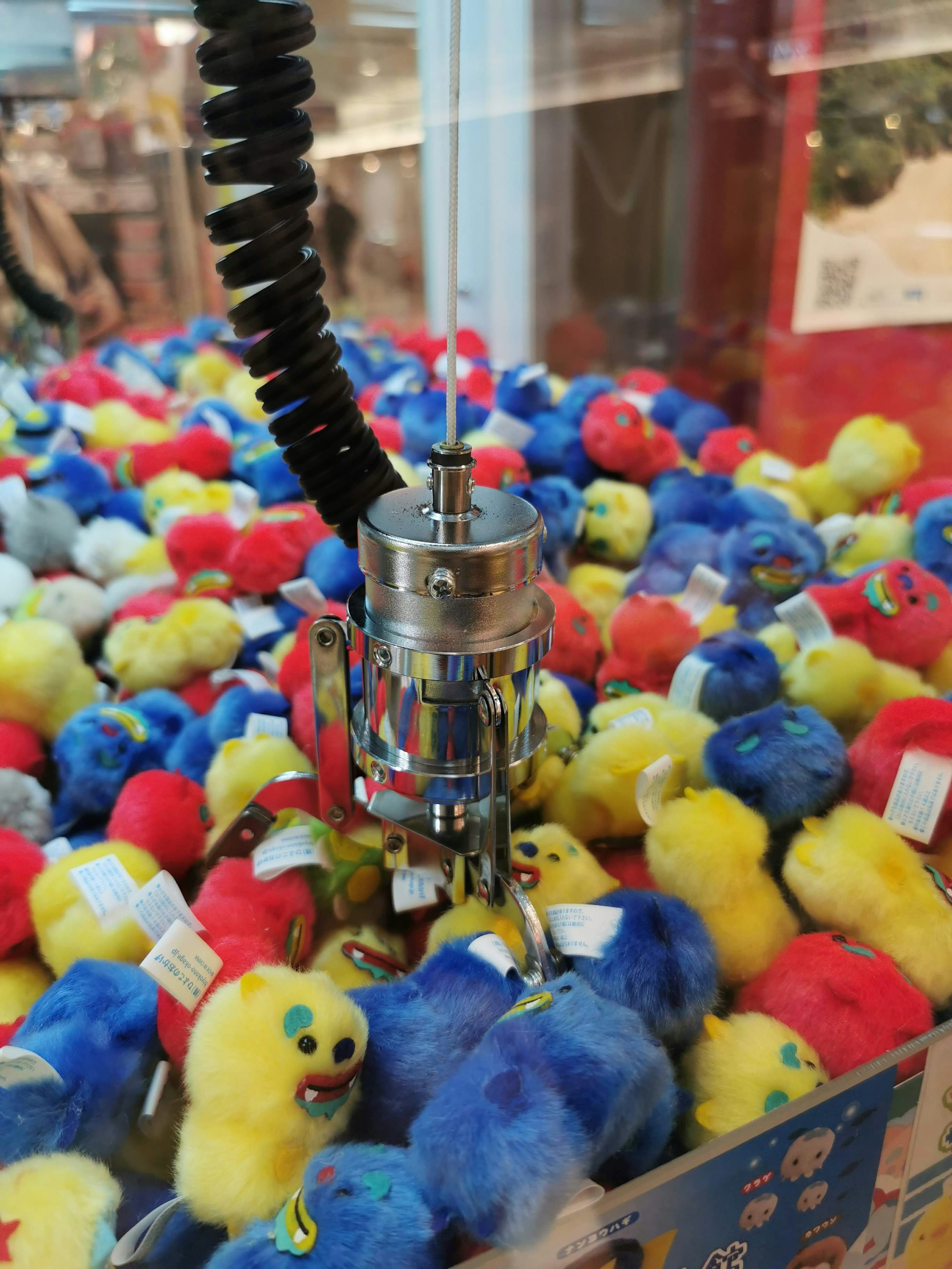 Colorful plush toys in a claw machine with a metallic claw