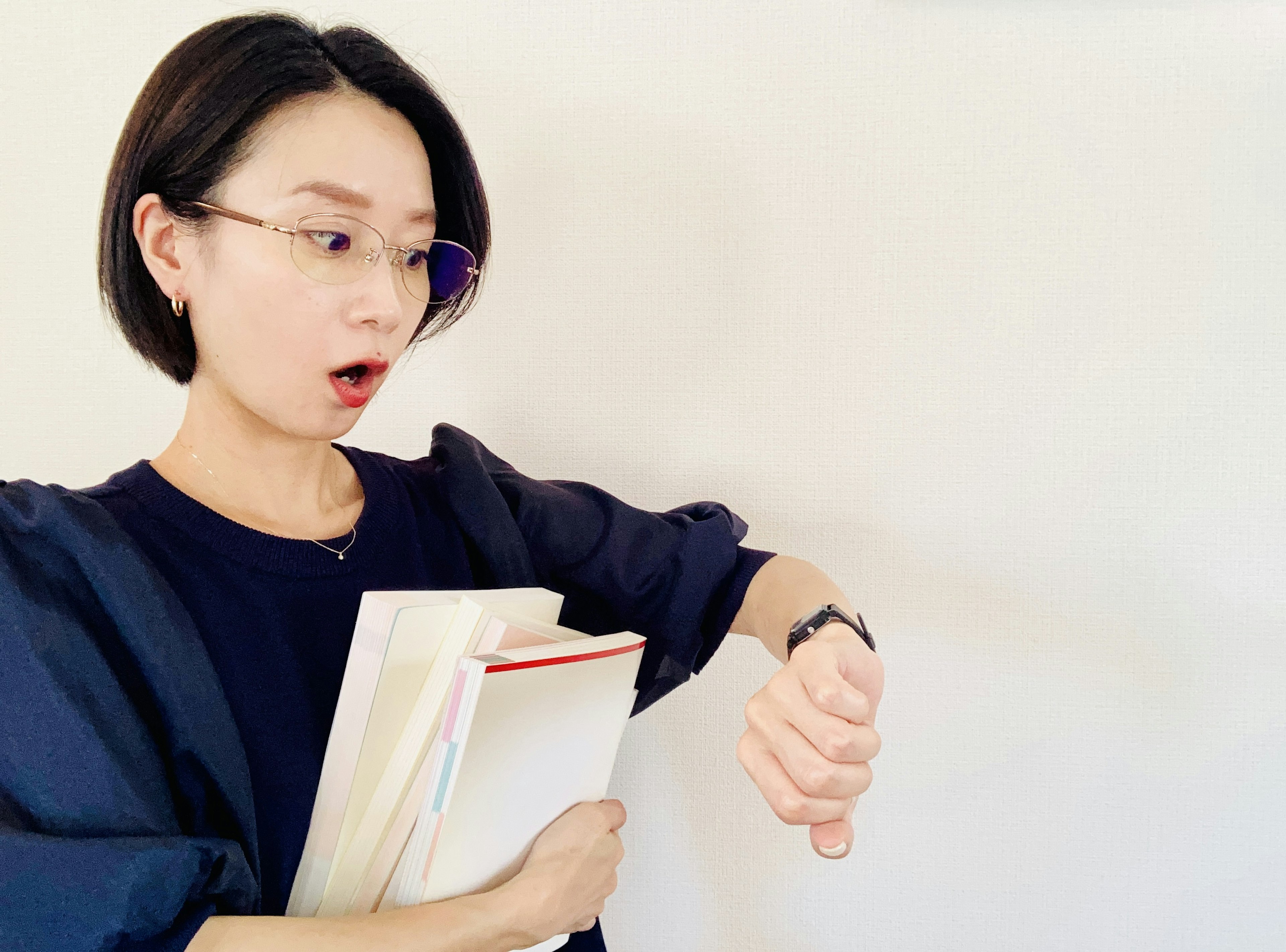 A surprised woman looking at her watch holding books