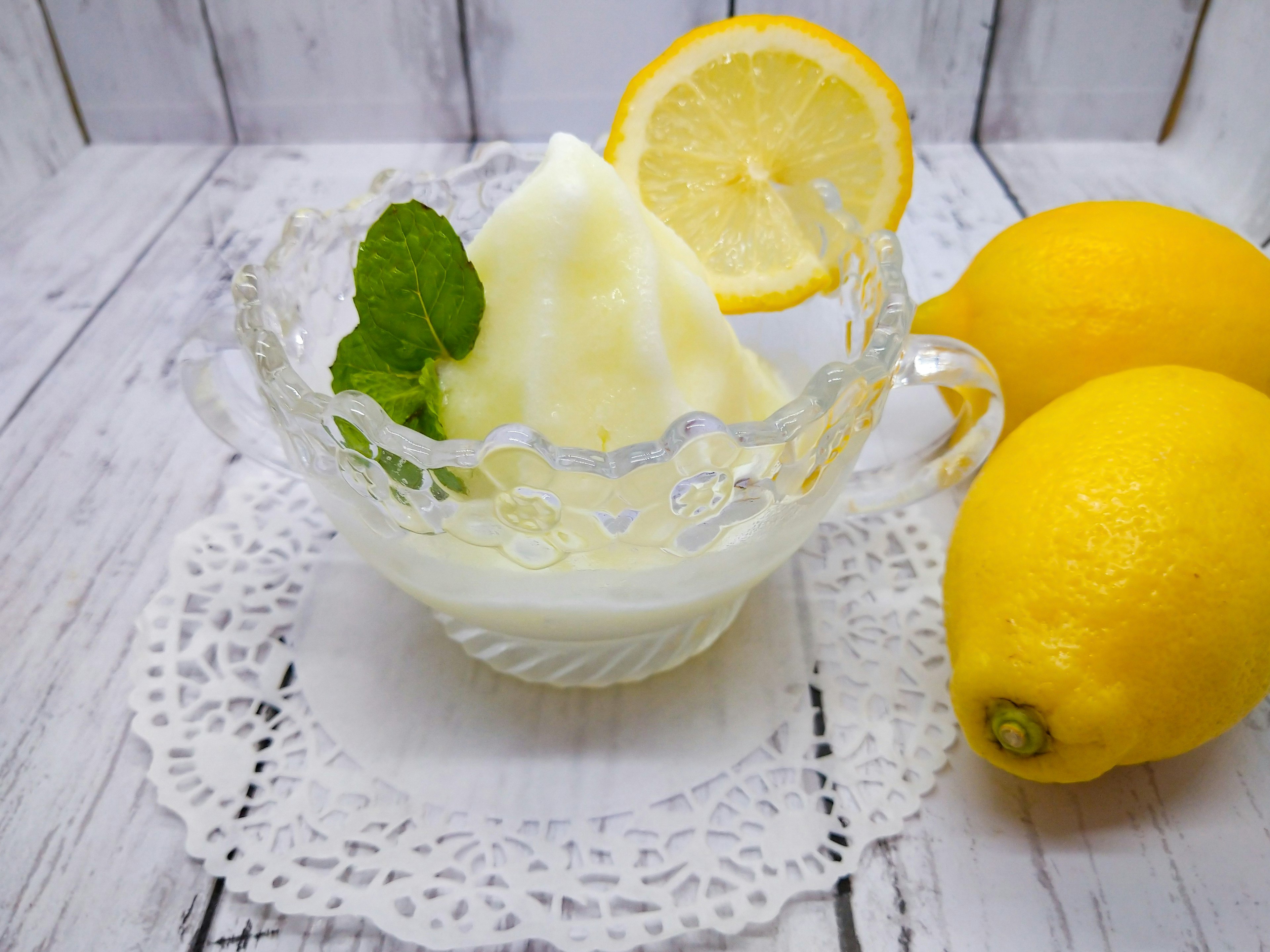 Zitronensorbet in einer klaren Glasschale garniert mit Minzblättern und Zitronenscheiben