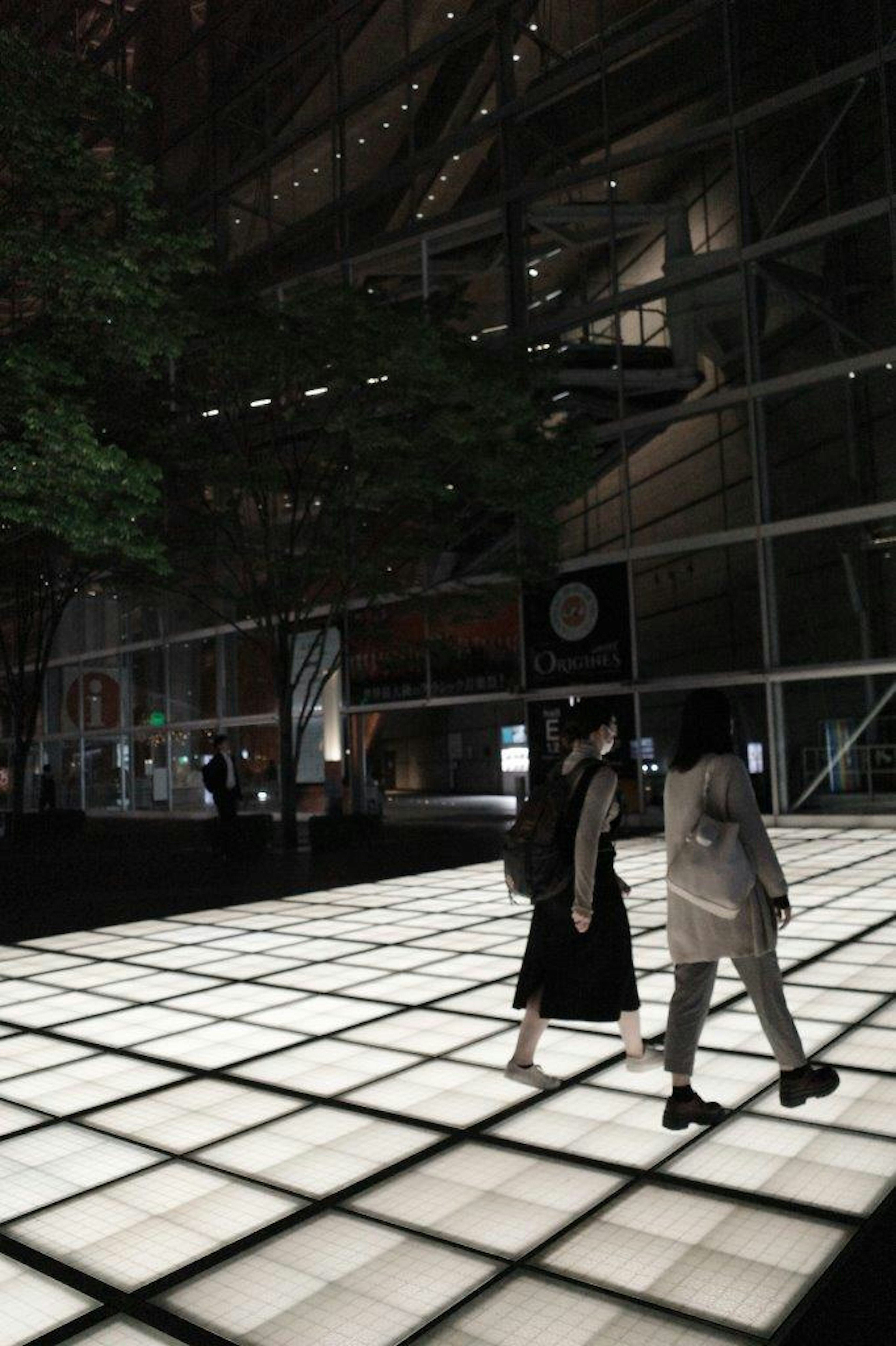 Two people walking on a bright grid-patterned floor