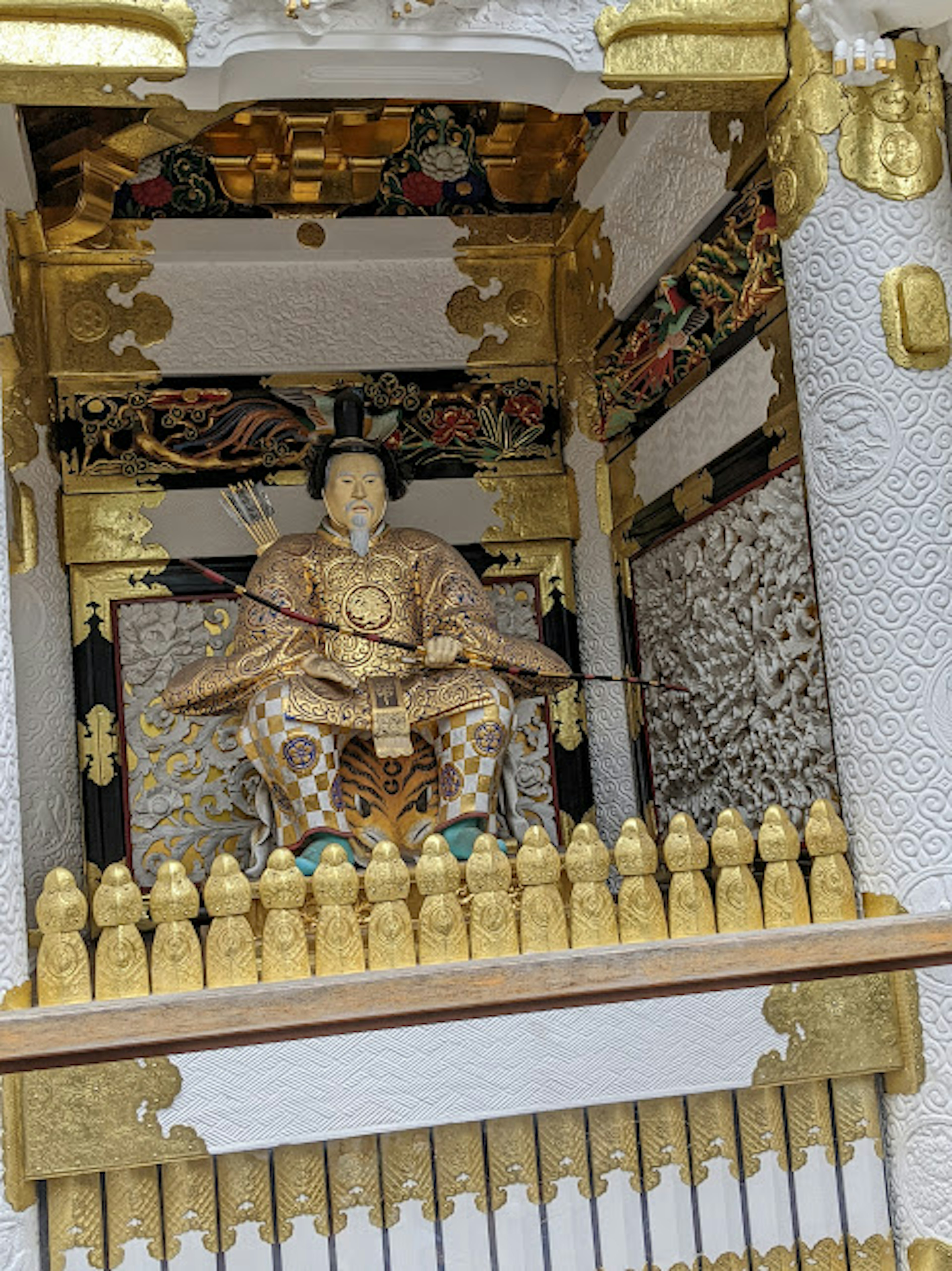 一個神社，裡面有一尊金色雕像，周圍環繞著華麗的裝飾