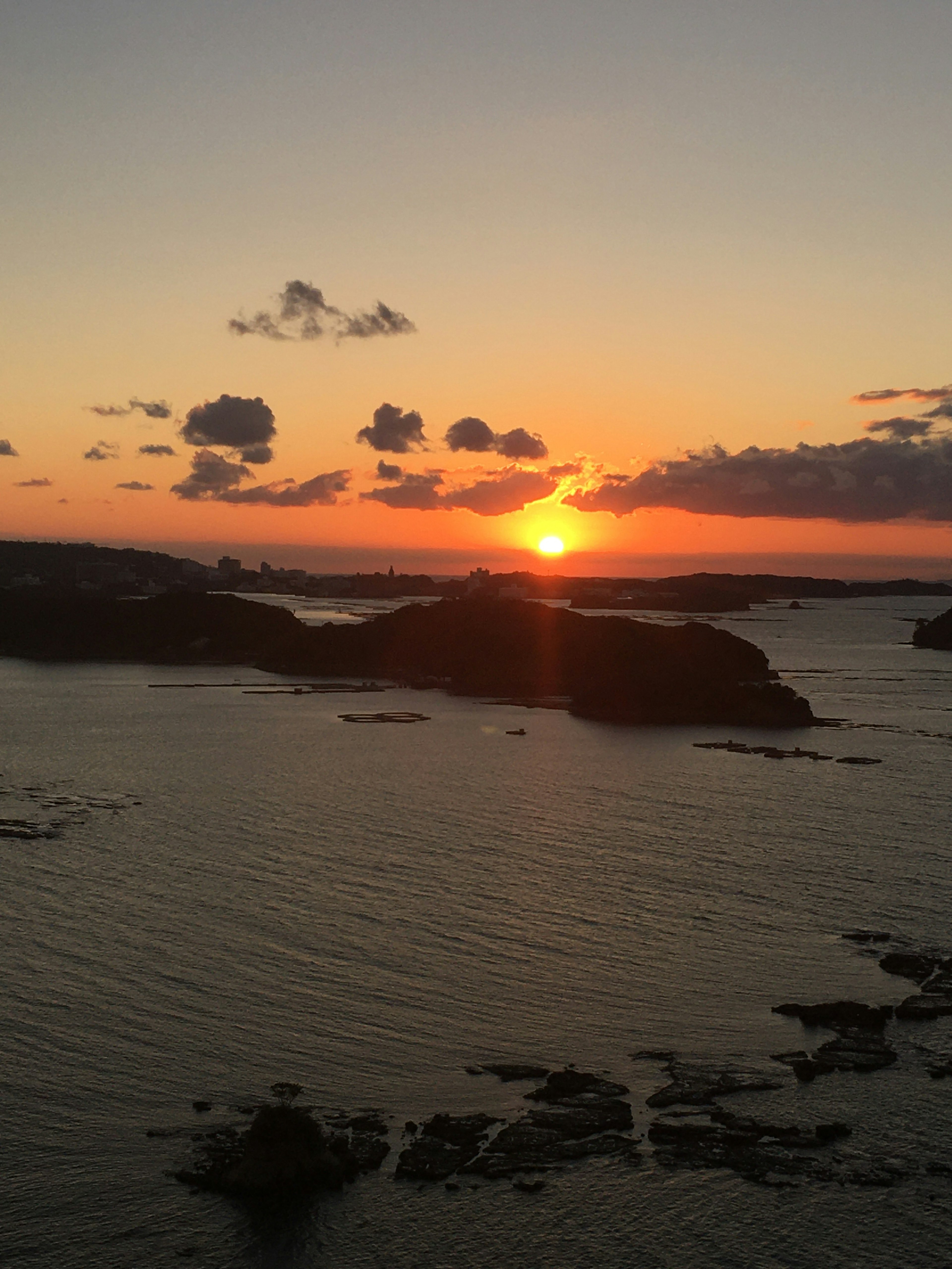 美麗的日落映照在海面上，有島嶼和雲彩