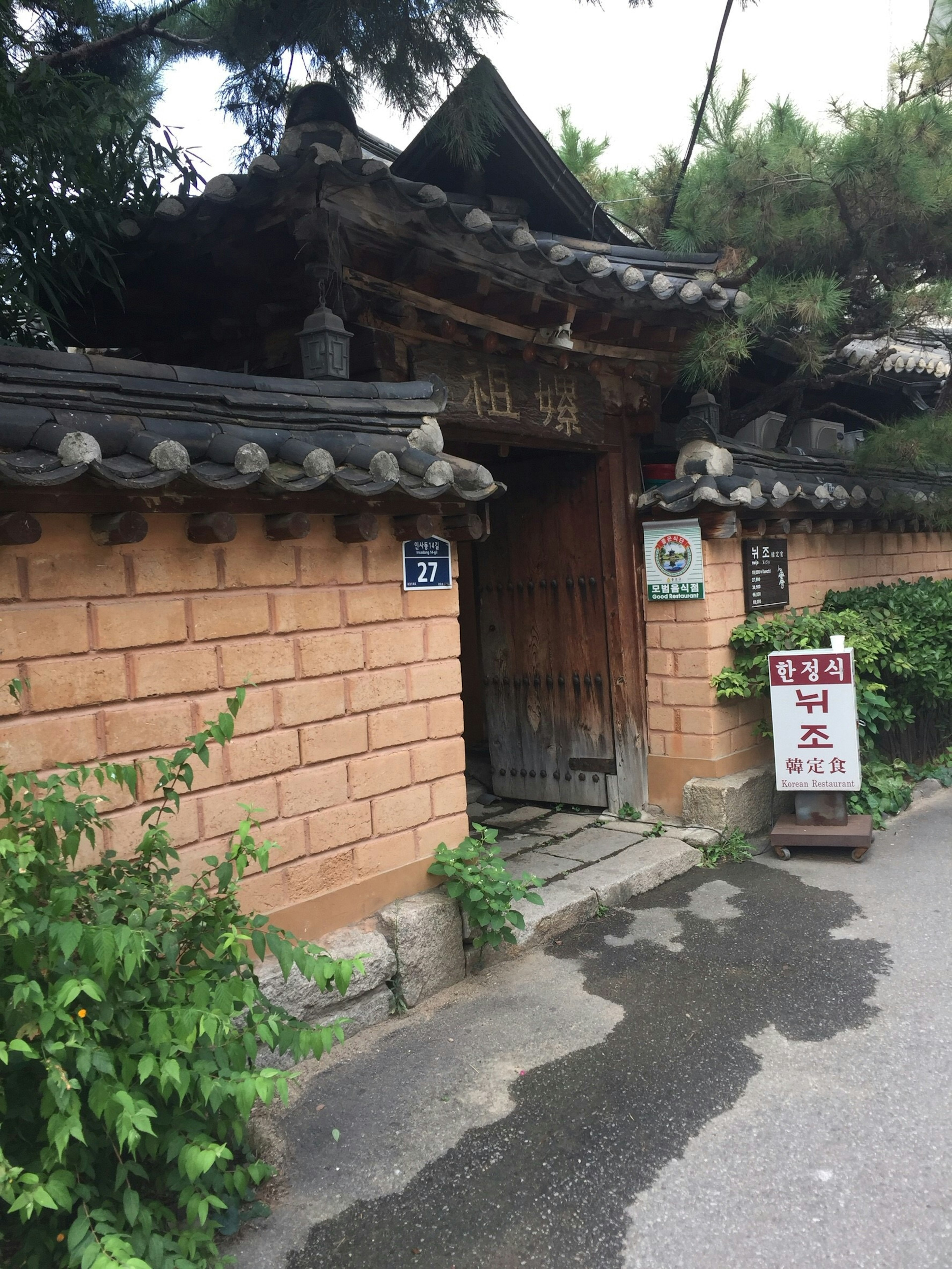 Entrada de una casa coreana tradicional con puerta de madera y techo de piedra