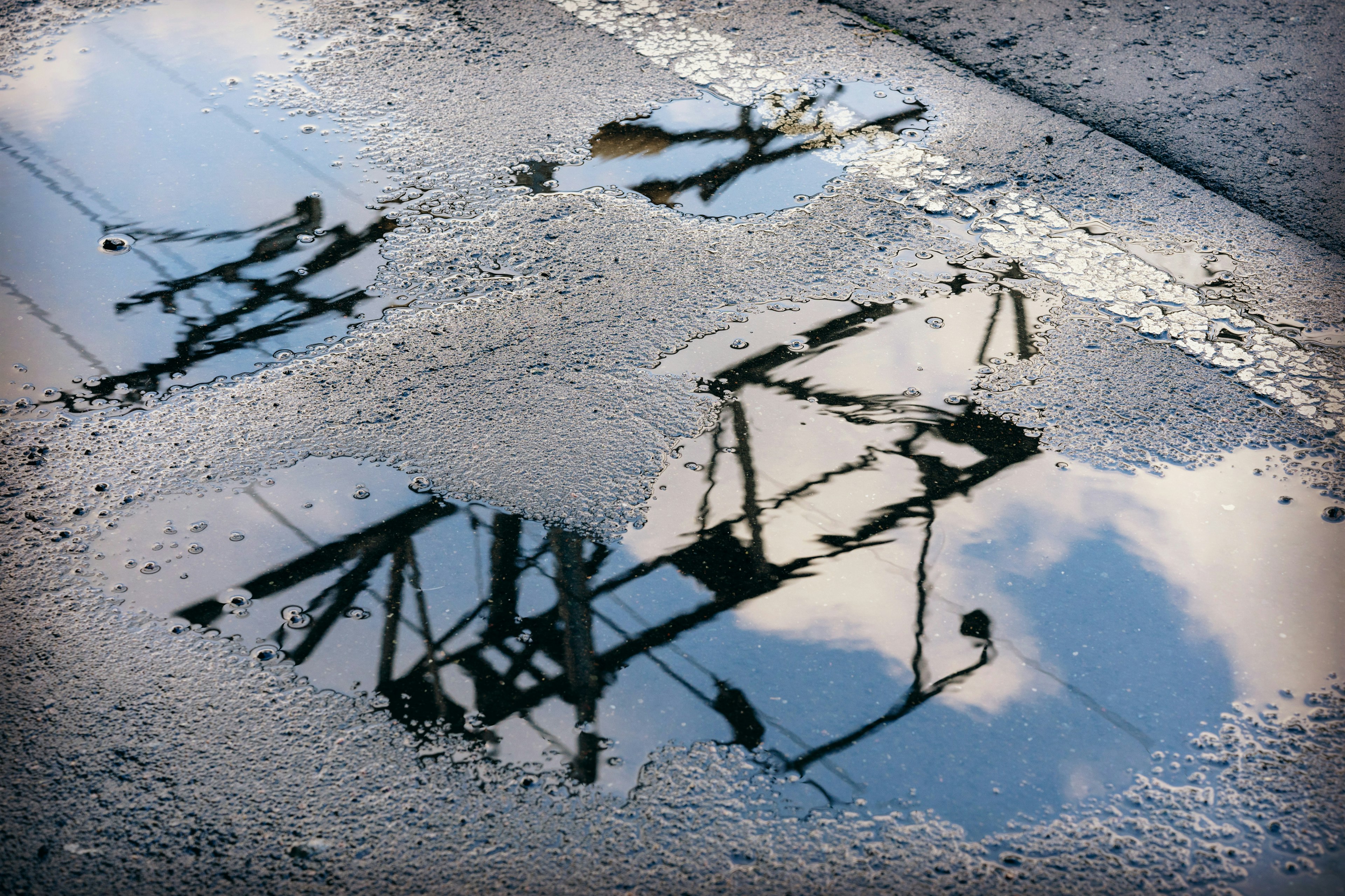 Reflet de lignes électriques dans une flaque d'eau avec ciel bleu