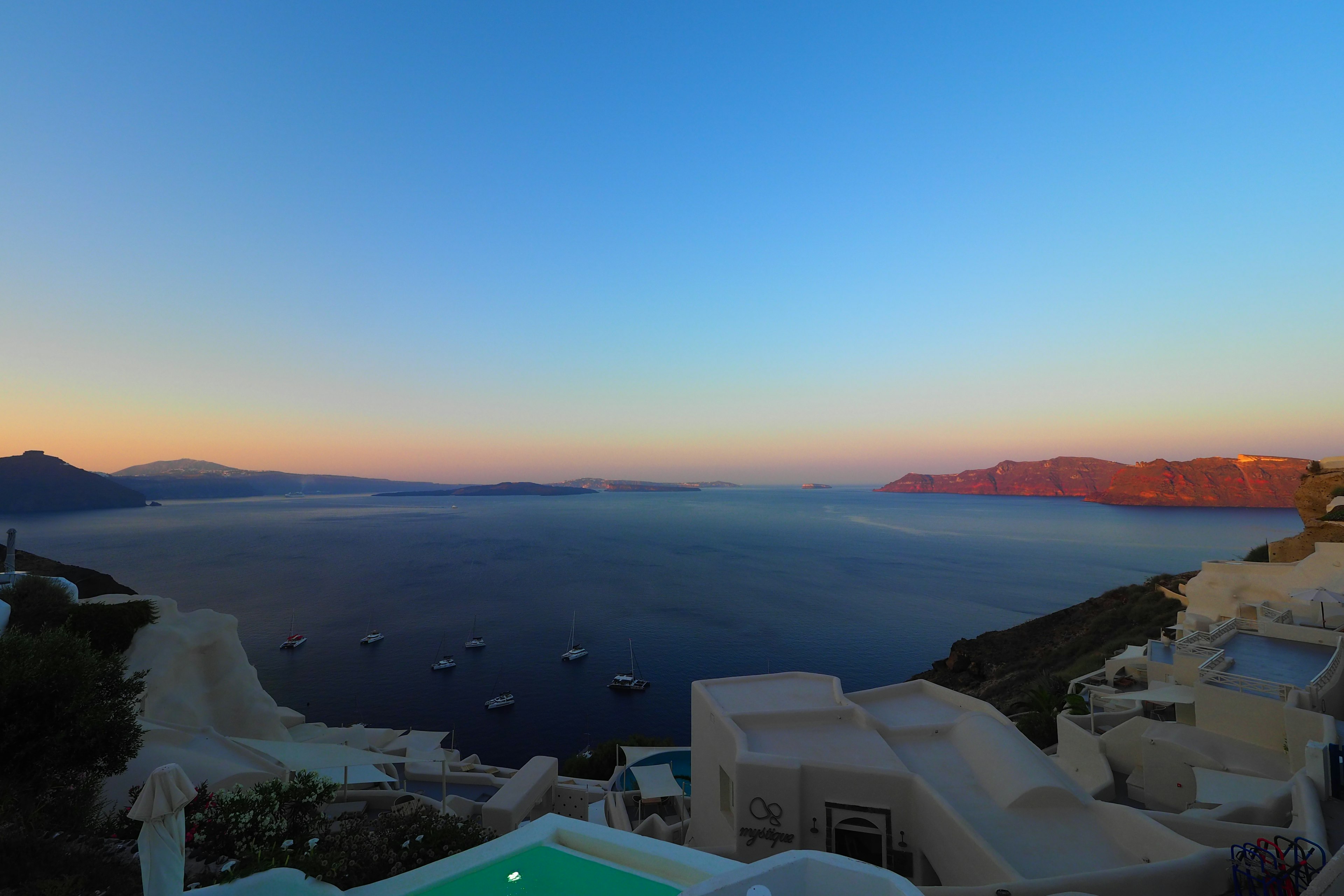 Vue magnifique du coucher de soleil sur la mer à Santorin avec des bâtiments blancs