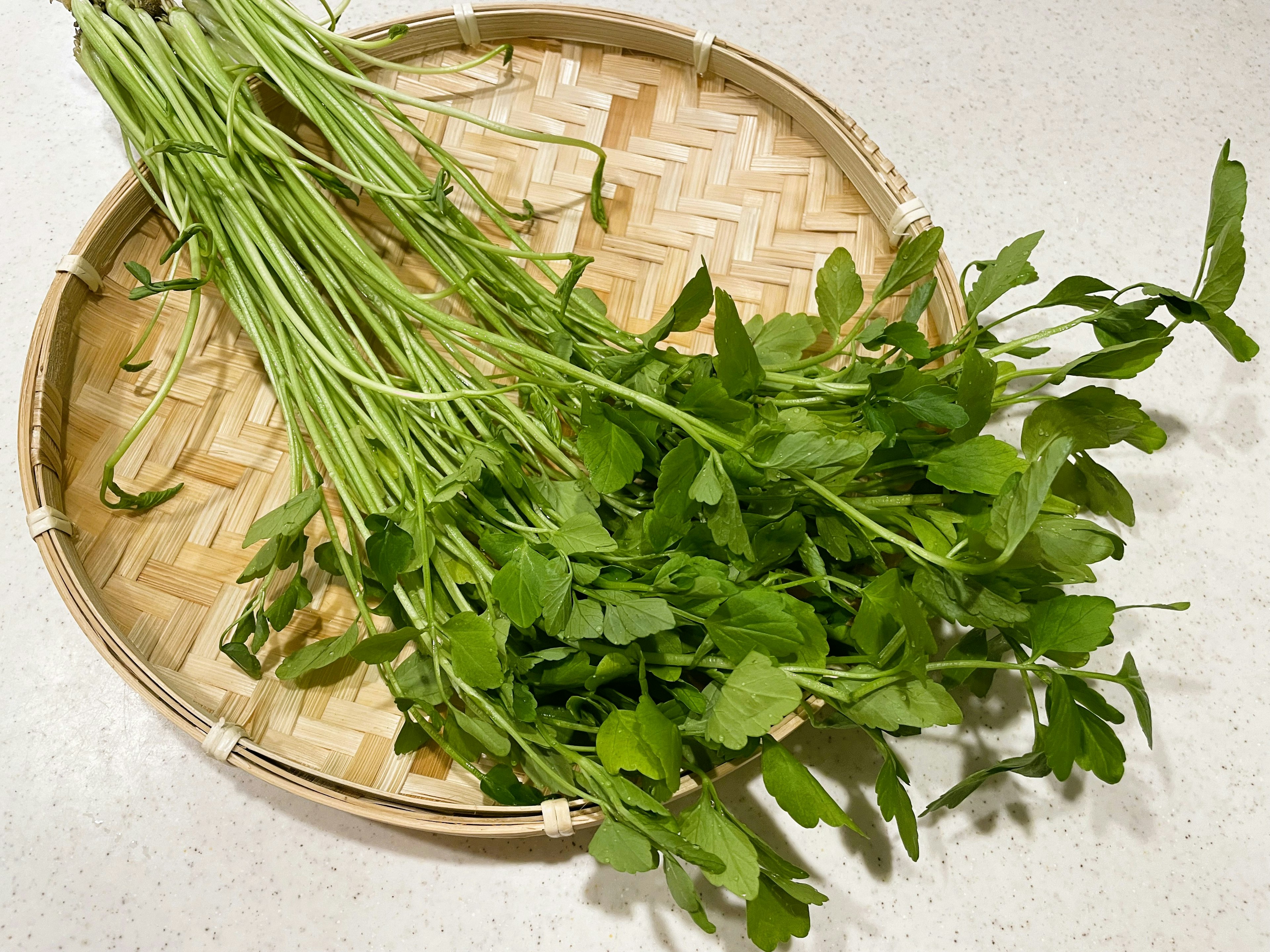 Fresh green herbs on a woven bamboo tray