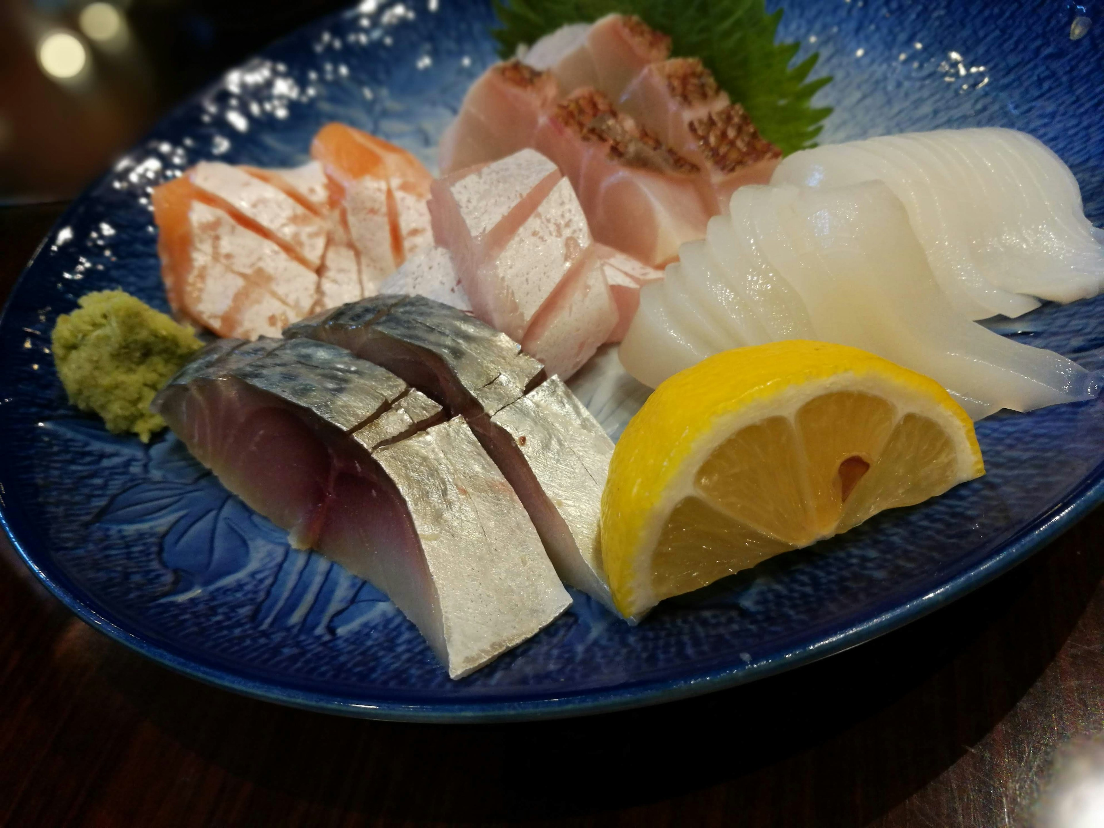 A colorful assortment of fresh sushi and sashimi on a blue plate