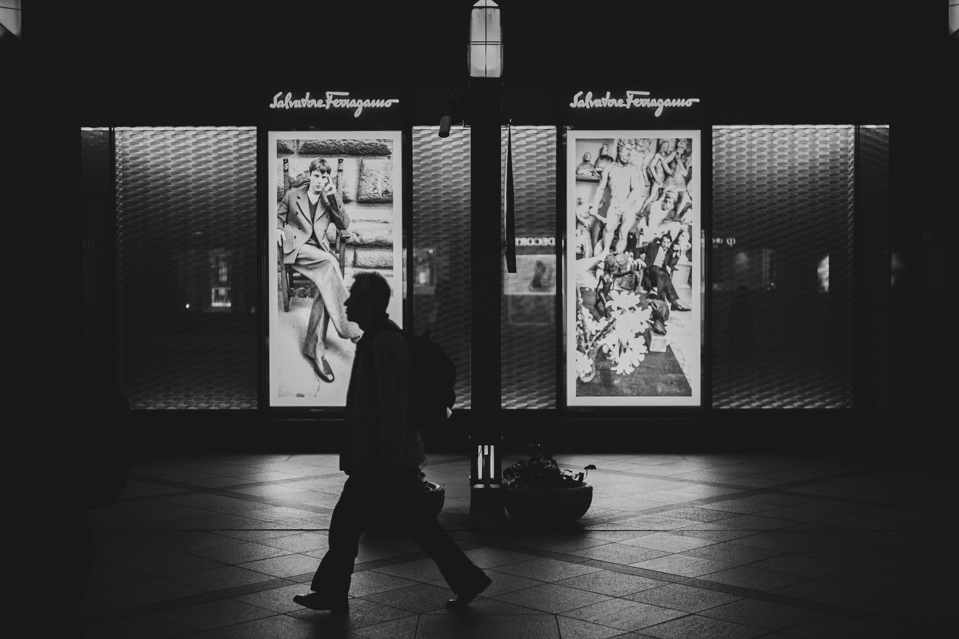 夜の街を歩く人影と明るいショーウィンドウ