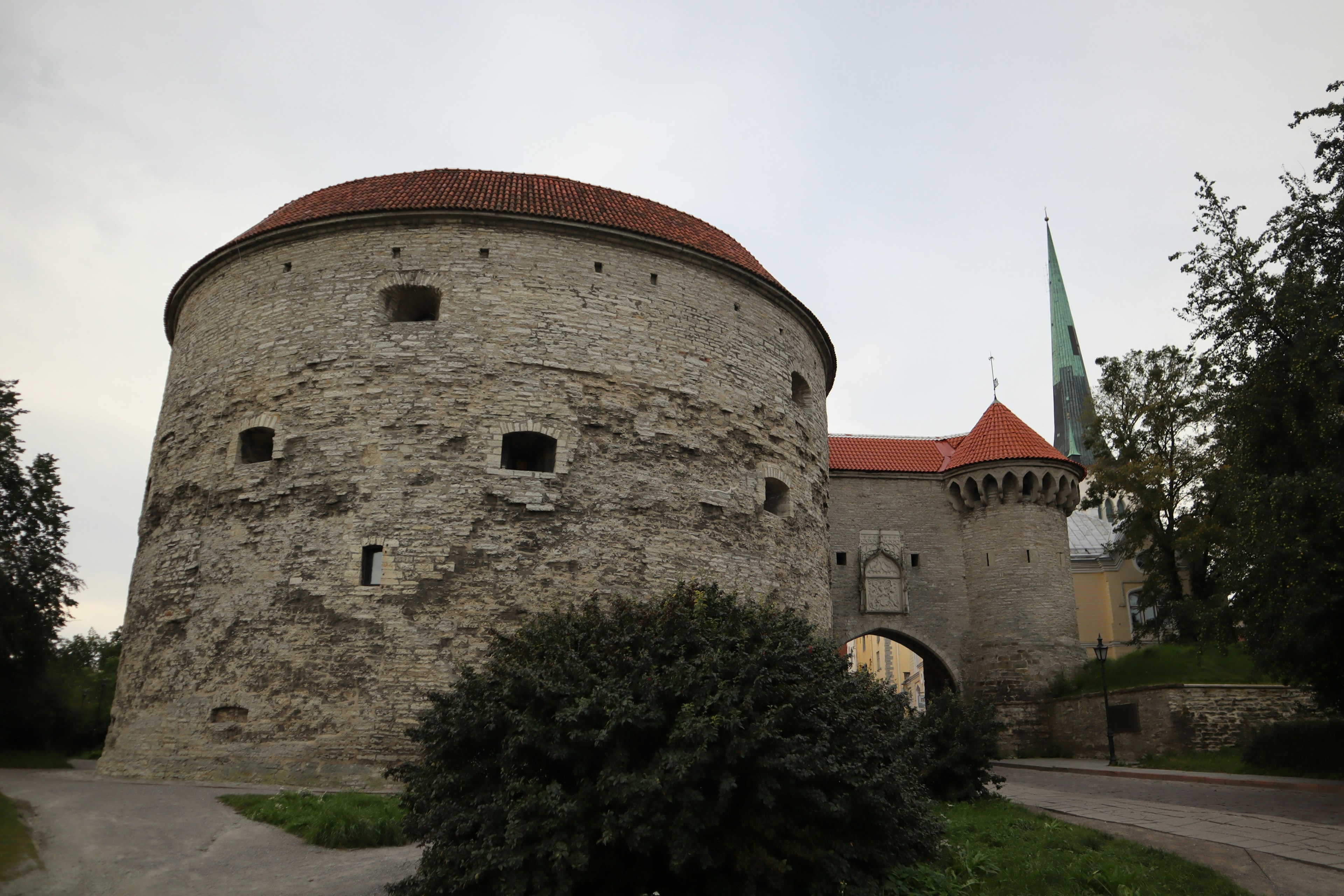 Landscape featuring a round tower with a stone wall and red roof