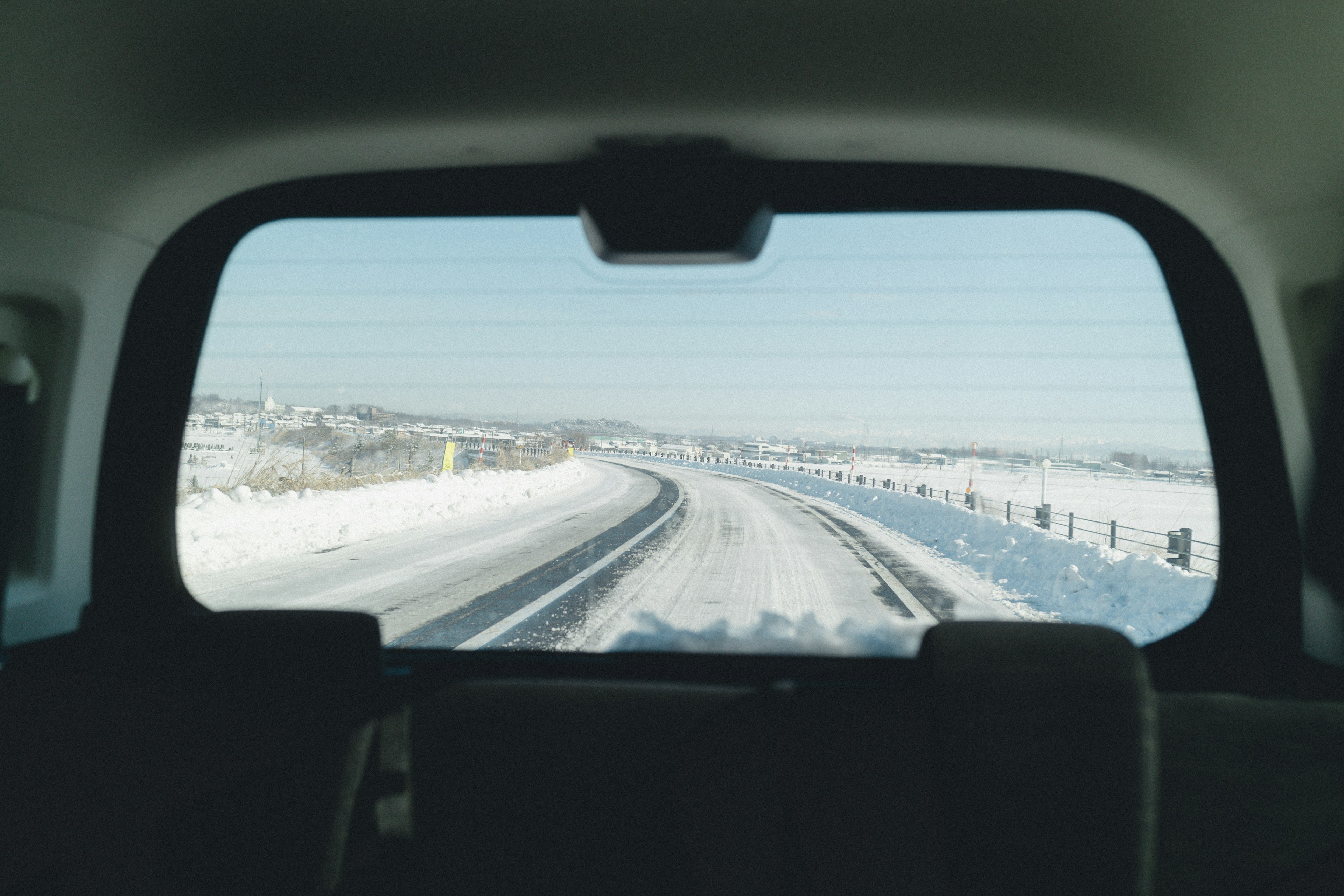 Blick vom Rücksitz eines Autos auf eine schneebedeckte Straße