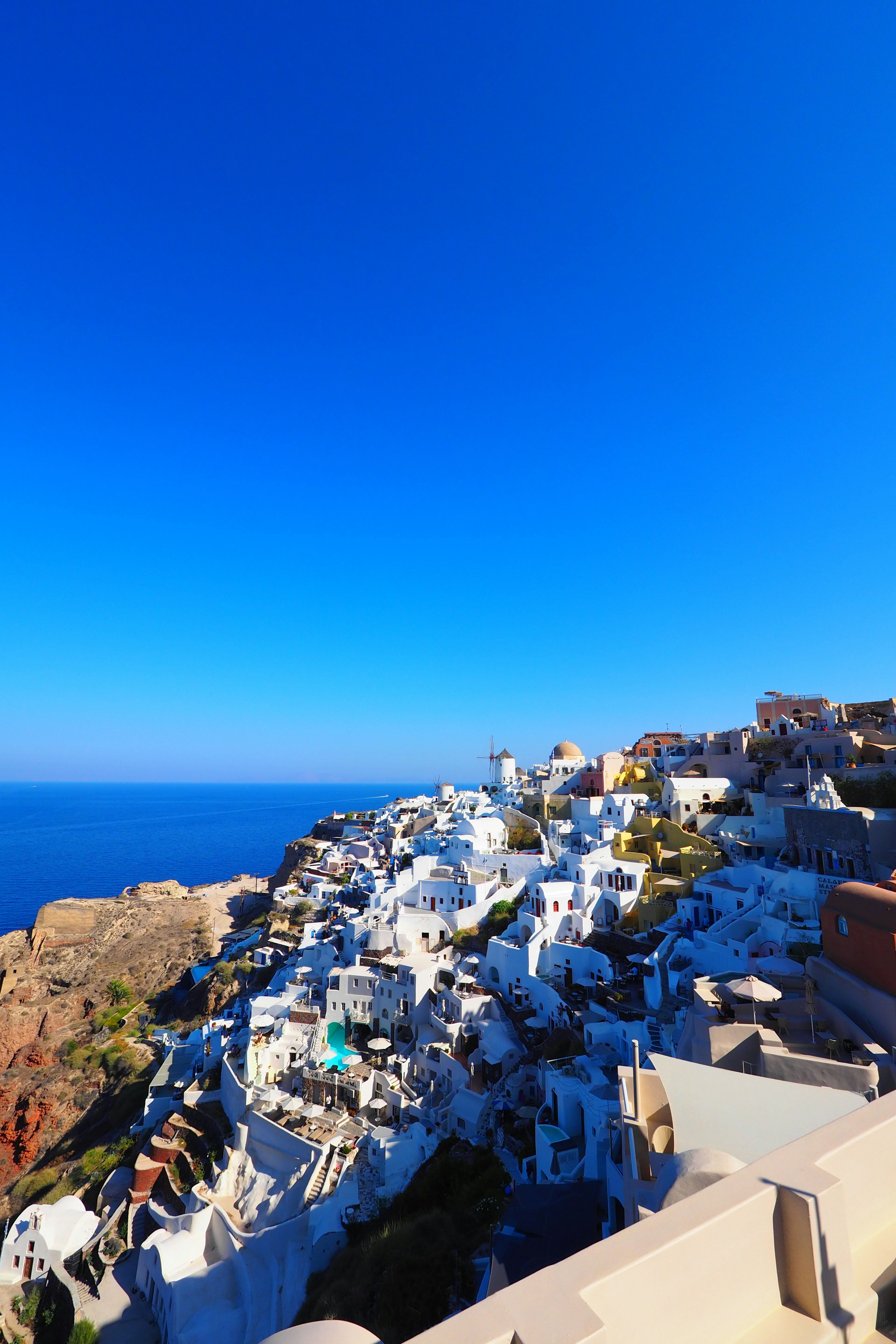 Vista costiera di Santorini con edifici bianchi e cielo blu chiaro