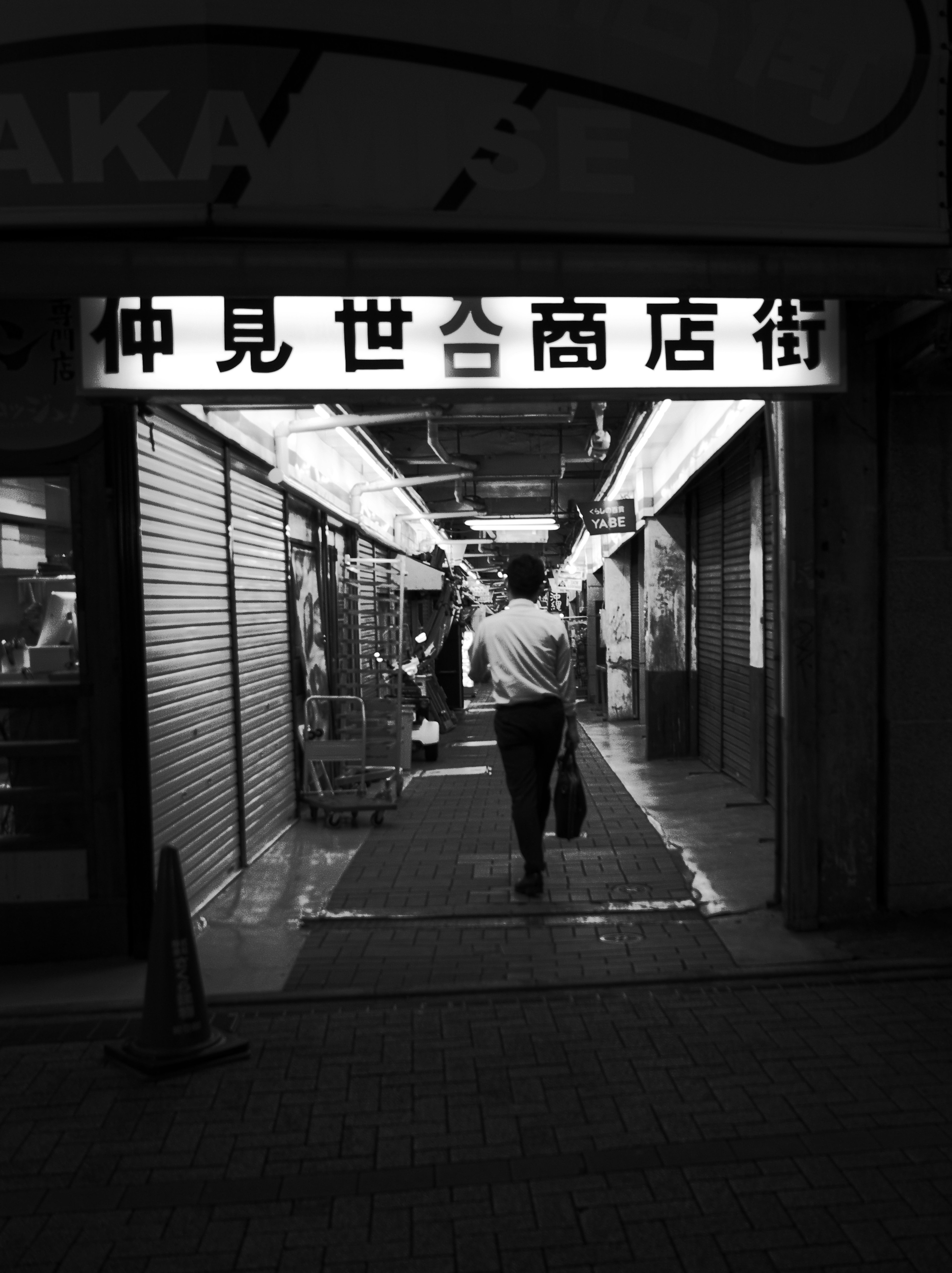 A man walking in a dark shopping street black and white photo