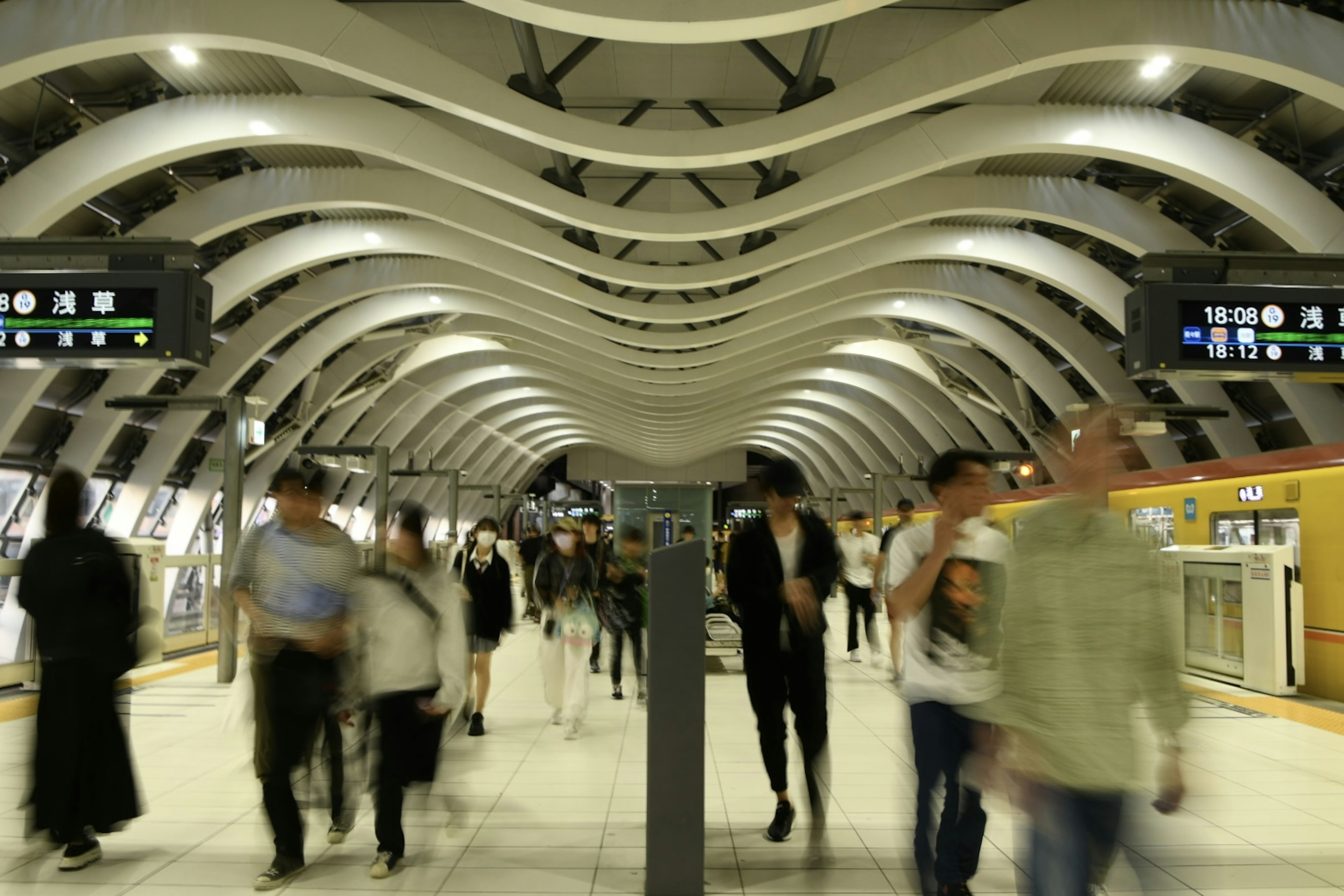 現代的な地下鉄駅の内部 人々が行き交う 鮮やかな照明と波型の天井