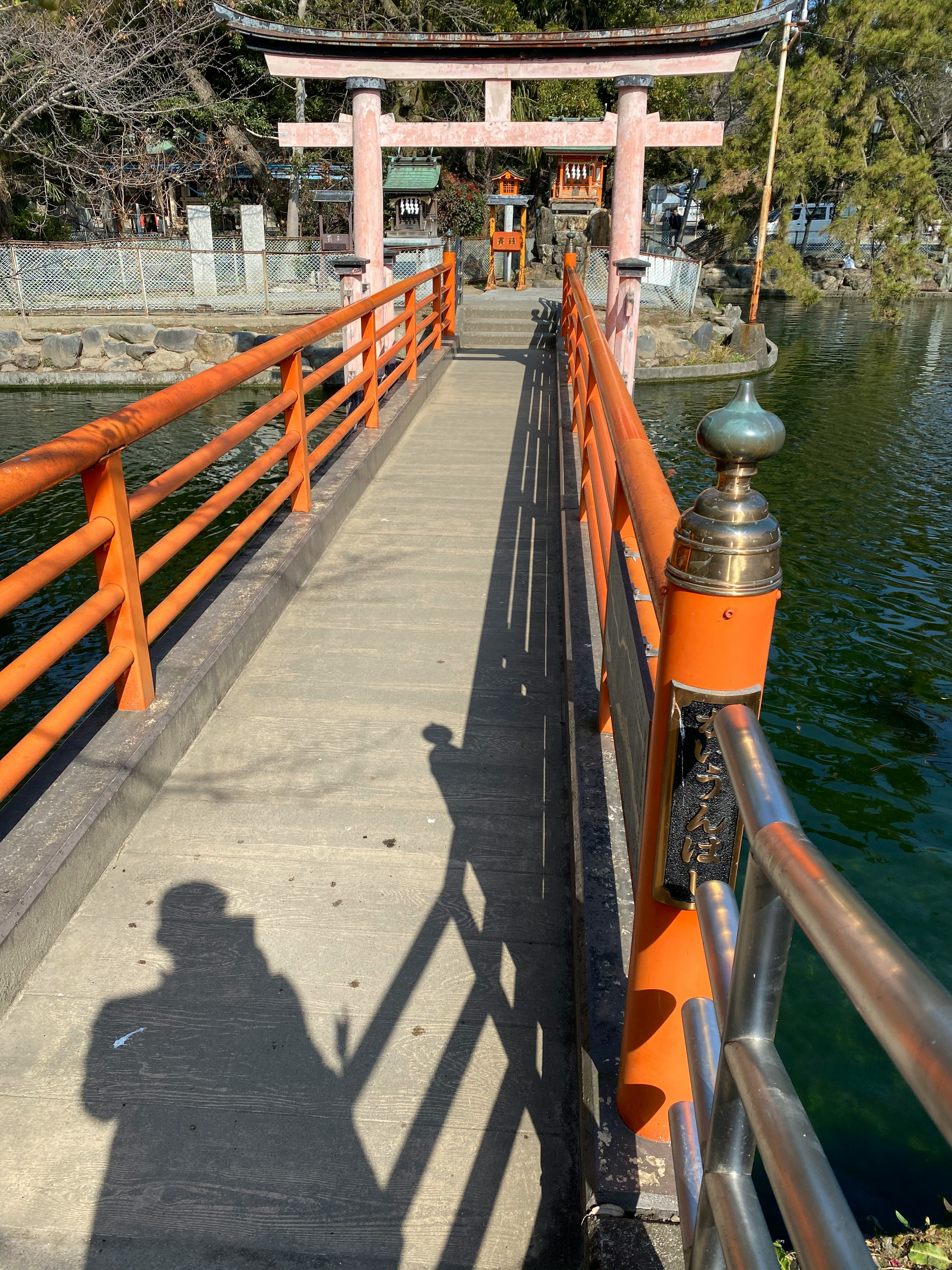 オレンジ色の手すりの橋が水辺にかかっている風景