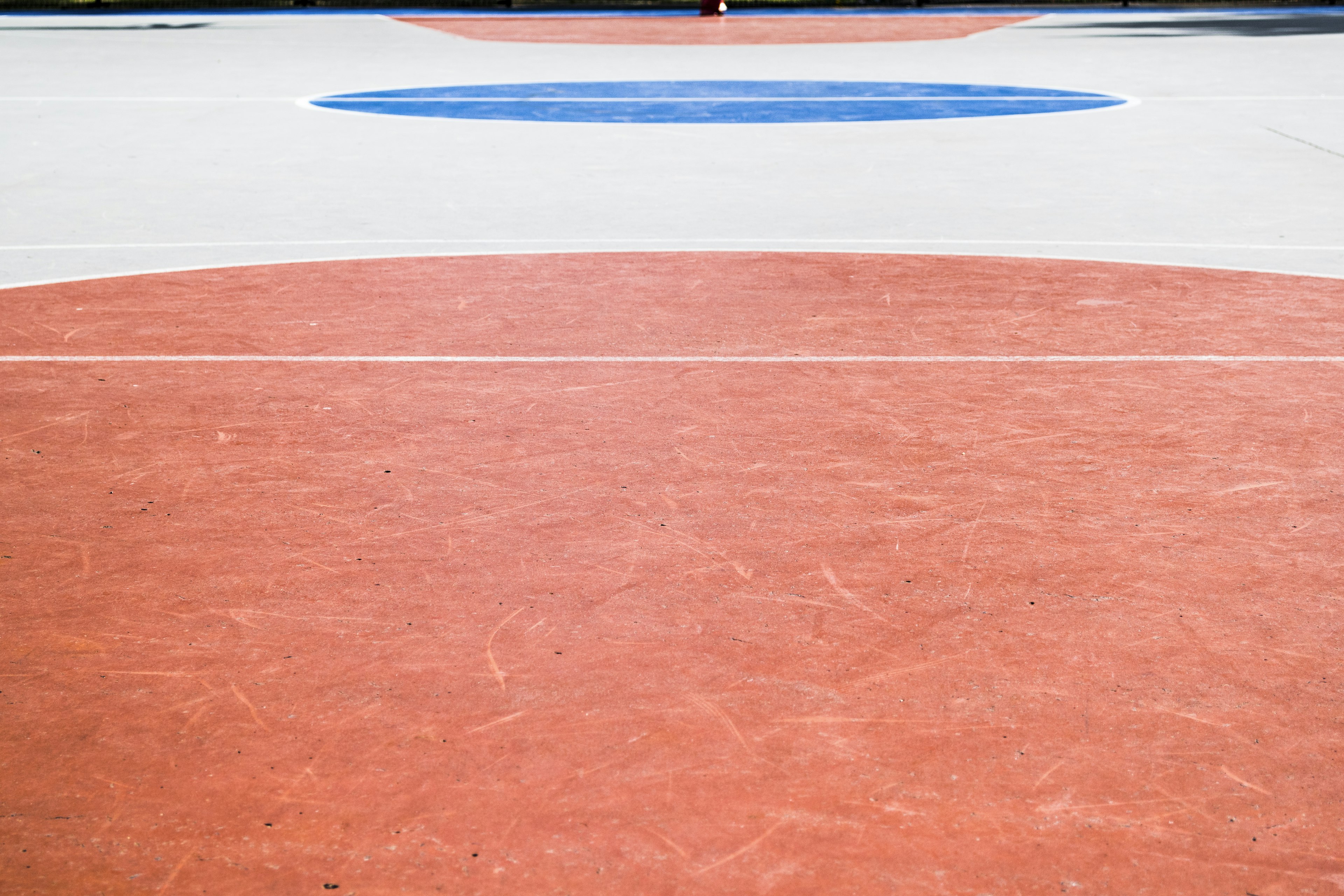 Red circular area with a blue circle on a sports court