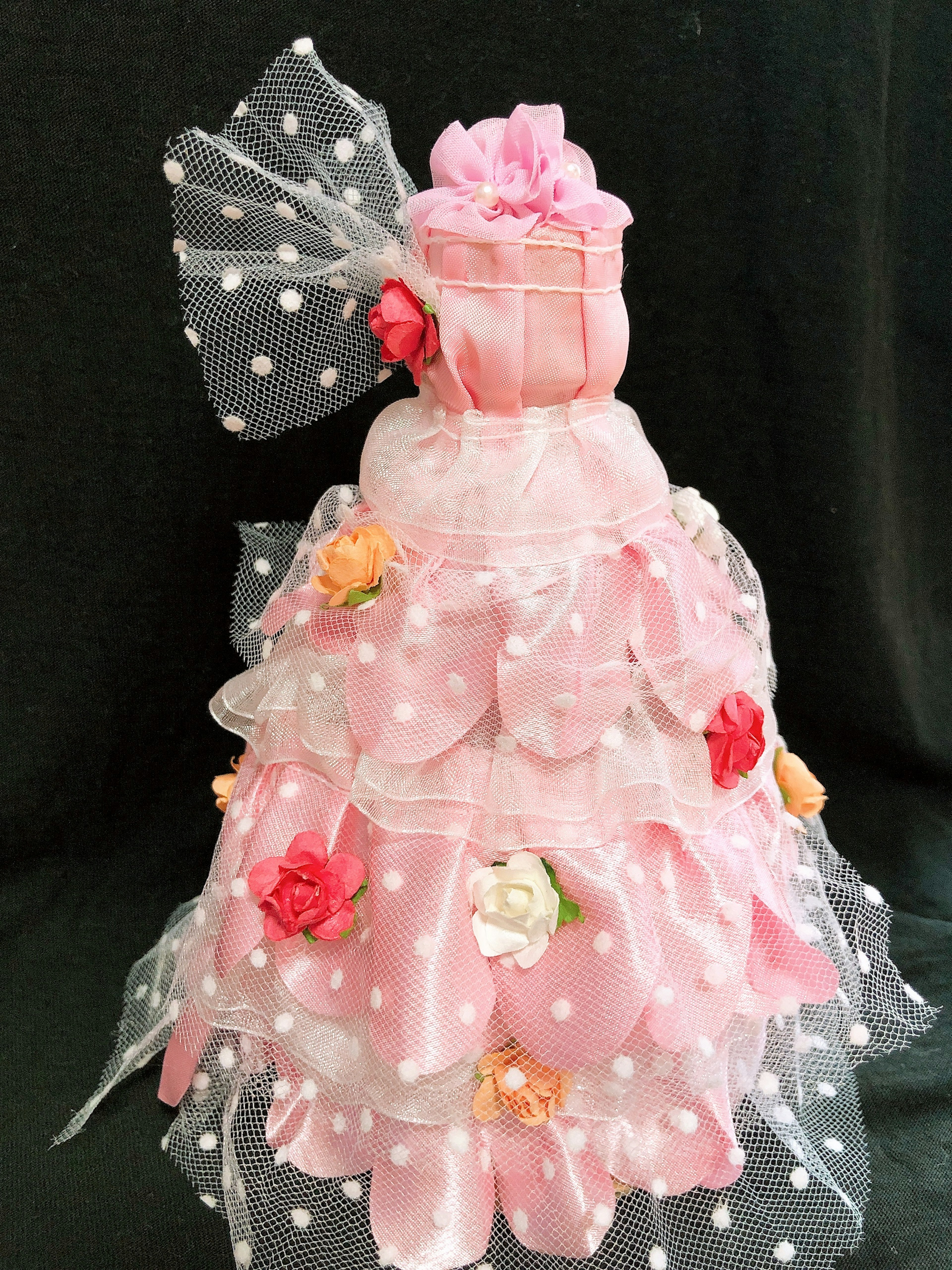 A doll dressed in pink with floral decorations