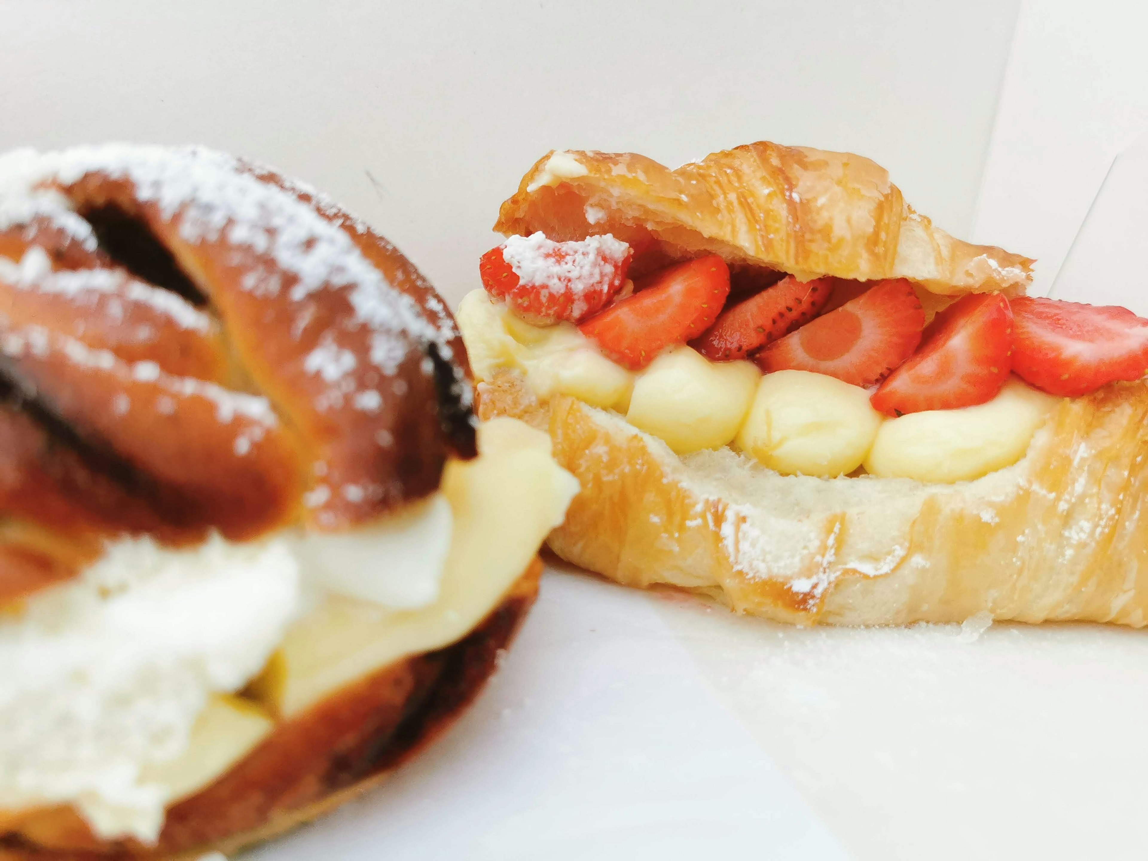 Sweet pastries featuring a cream-filled bun and a strawberry croissant