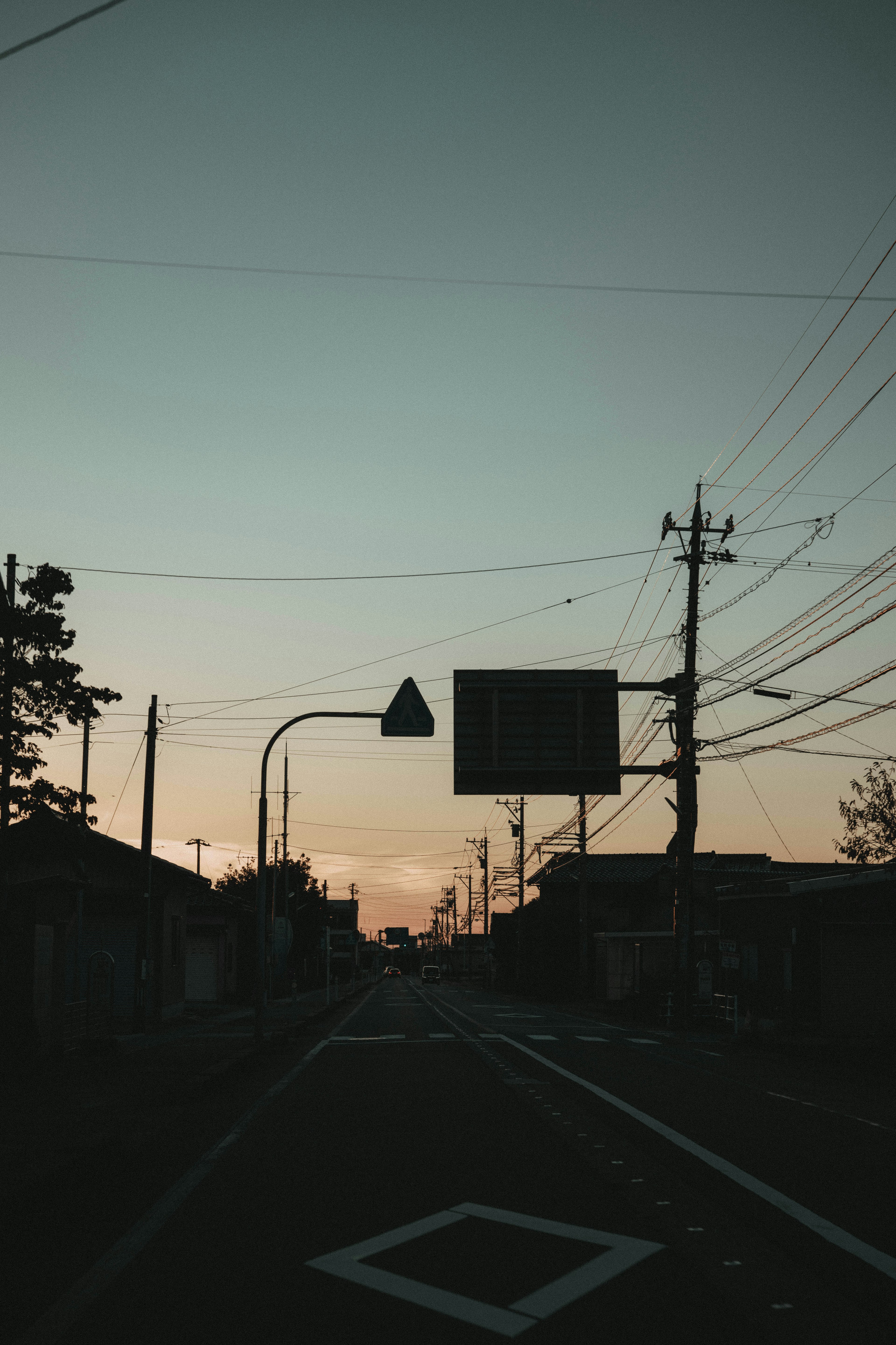 Silhouette of a road at dusk with power lines