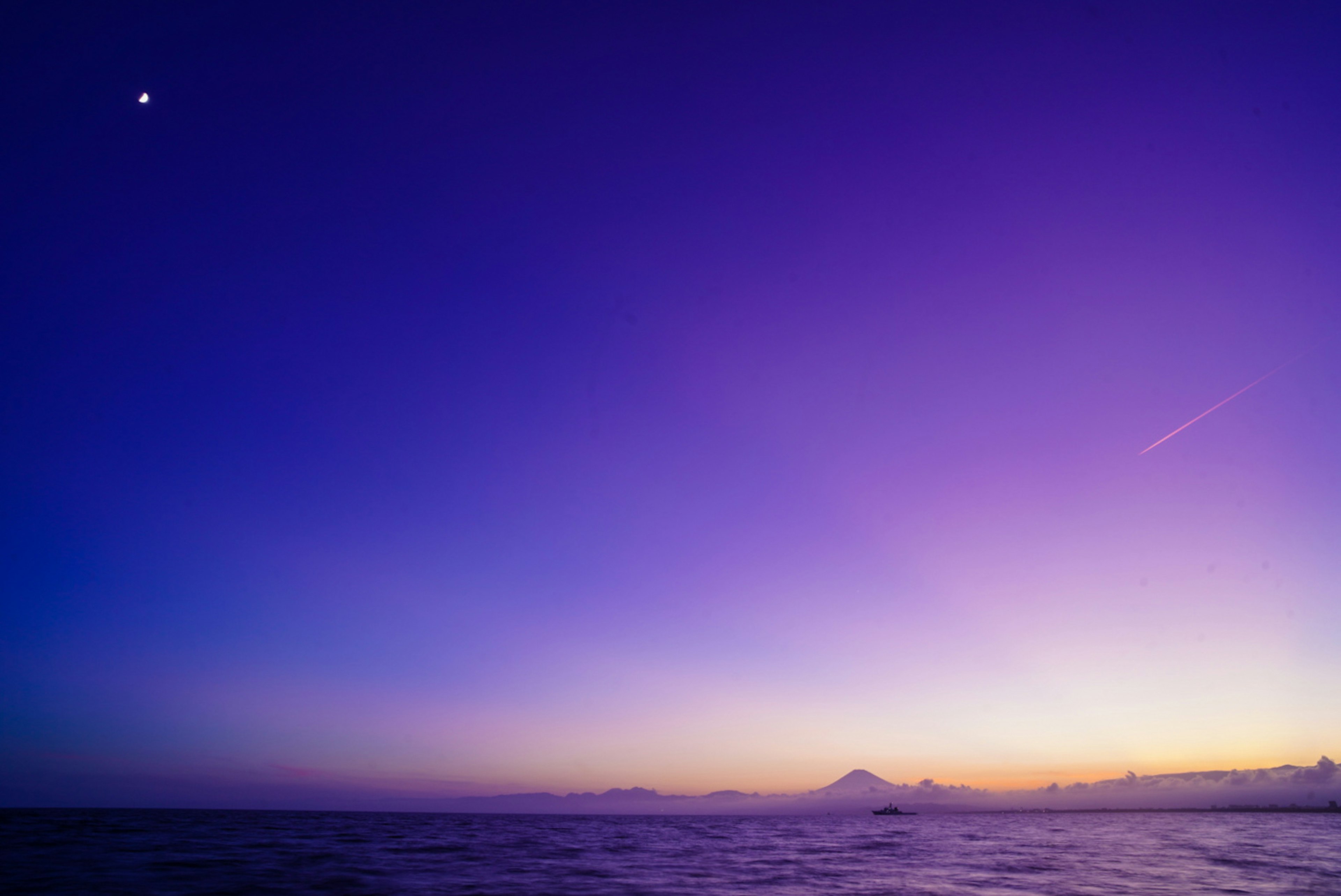 Beau ciel violet et paysage océanique avec une lune visible au crépuscule