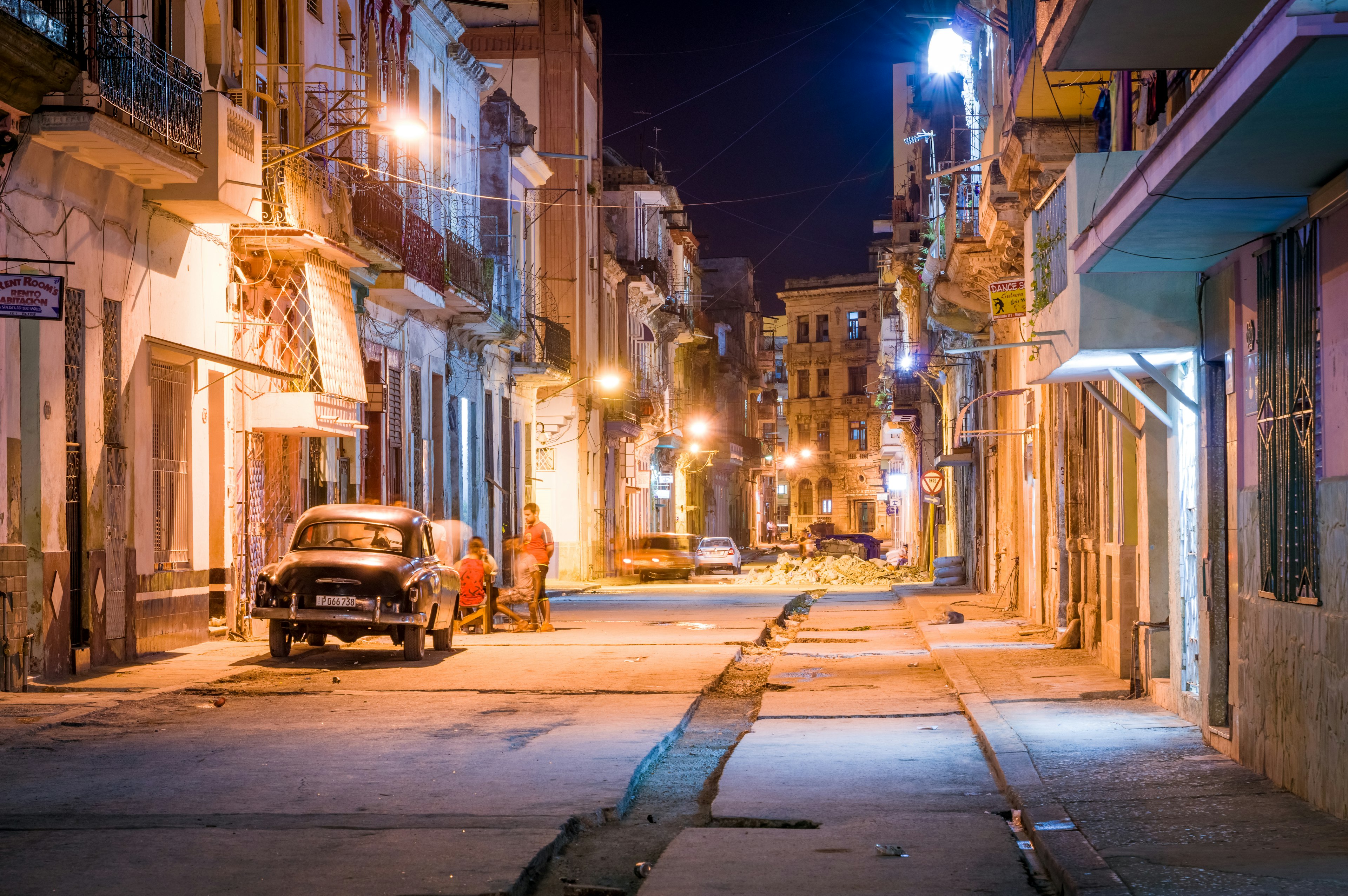 Quiet street in Havana at night featuring vintage car and street lights