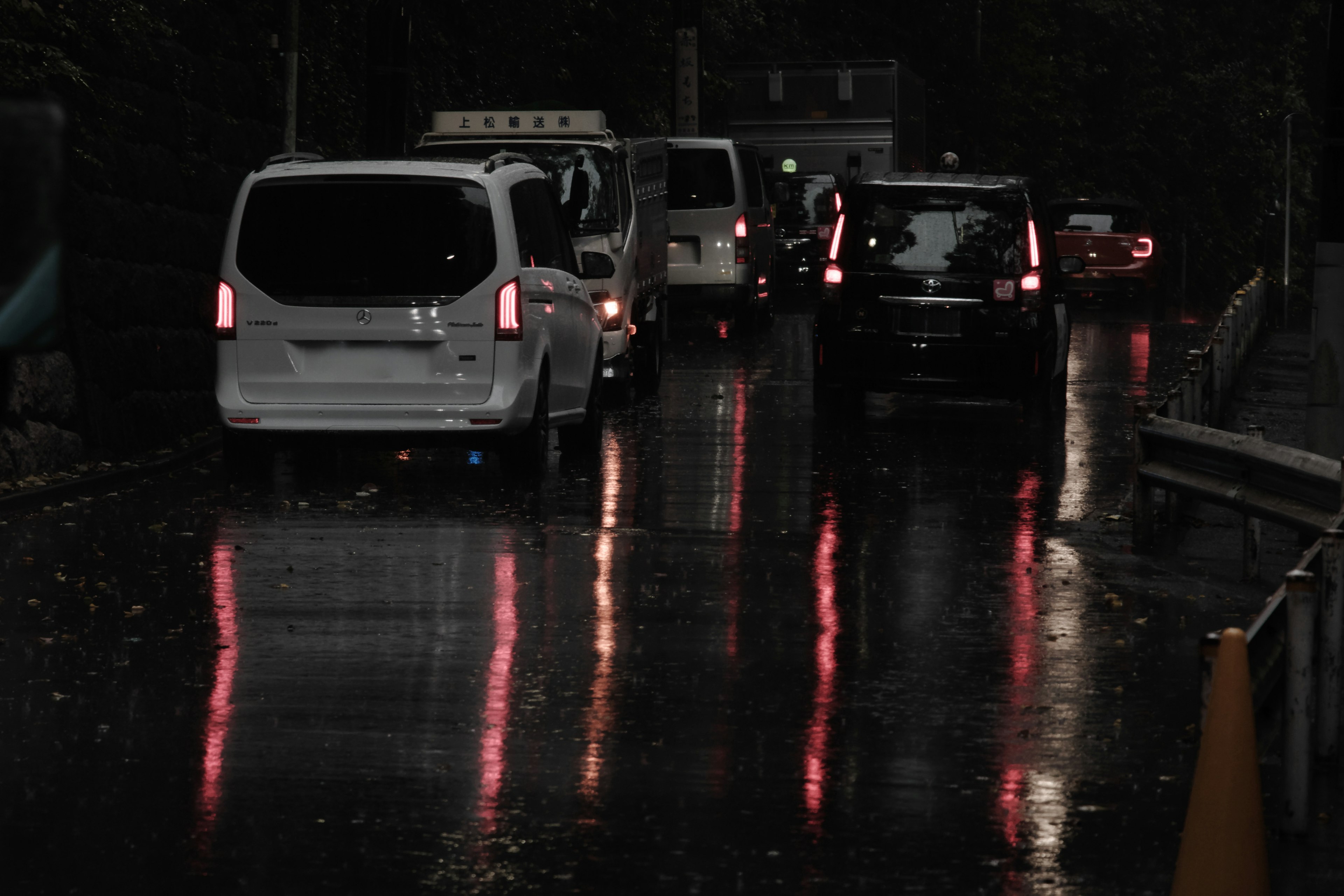 Fila de coches en una carretera mojada con reflejos de la lluvia