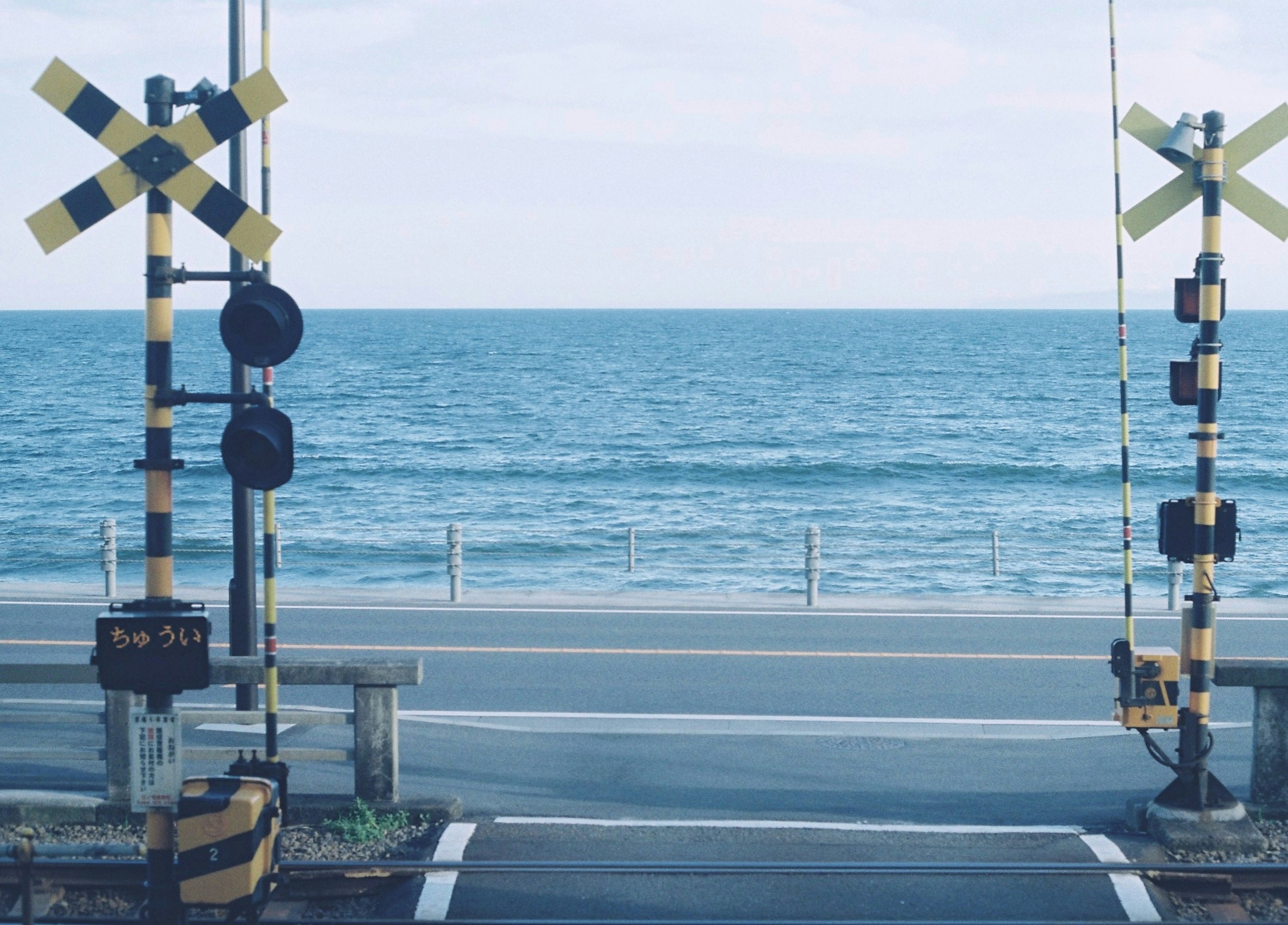 海を背景にした踏切の景色黄色と黒の警告標識