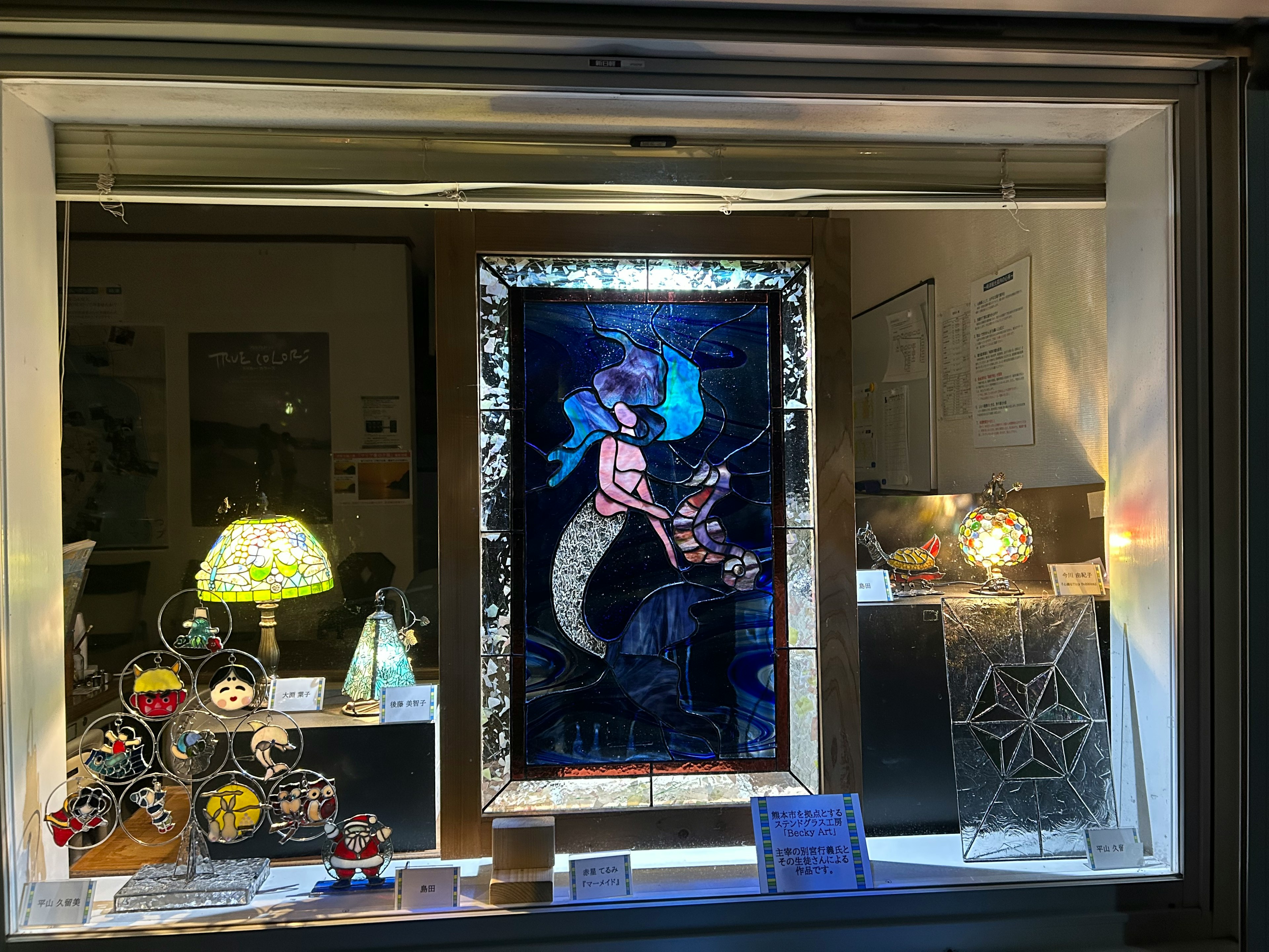 Une belle œuvre d'art de sirène exposée dans une vitrine de magasin avec divers luminaires