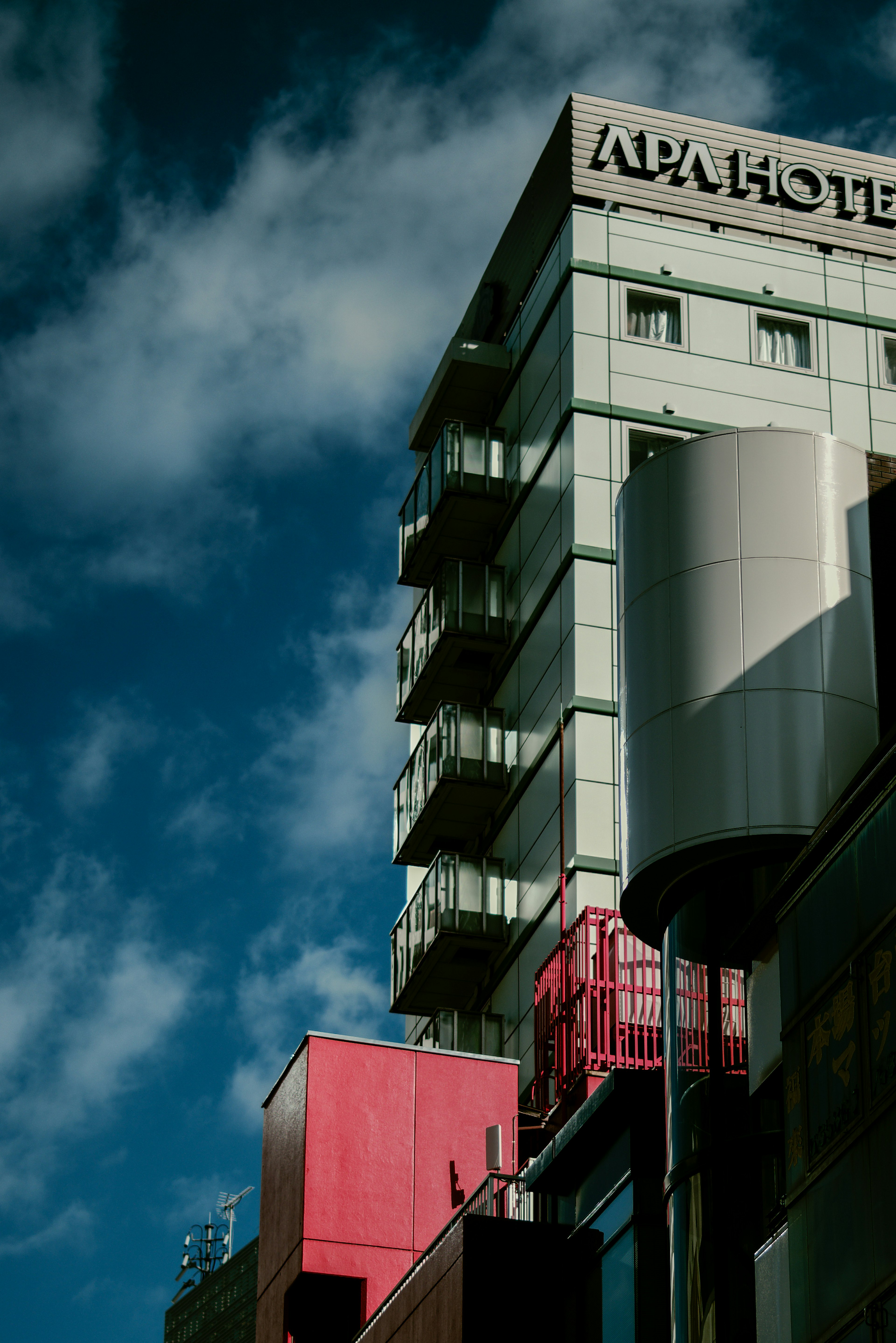 Vue extérieure de l'hôtel APA avec des murs rouges sous un ciel bleu