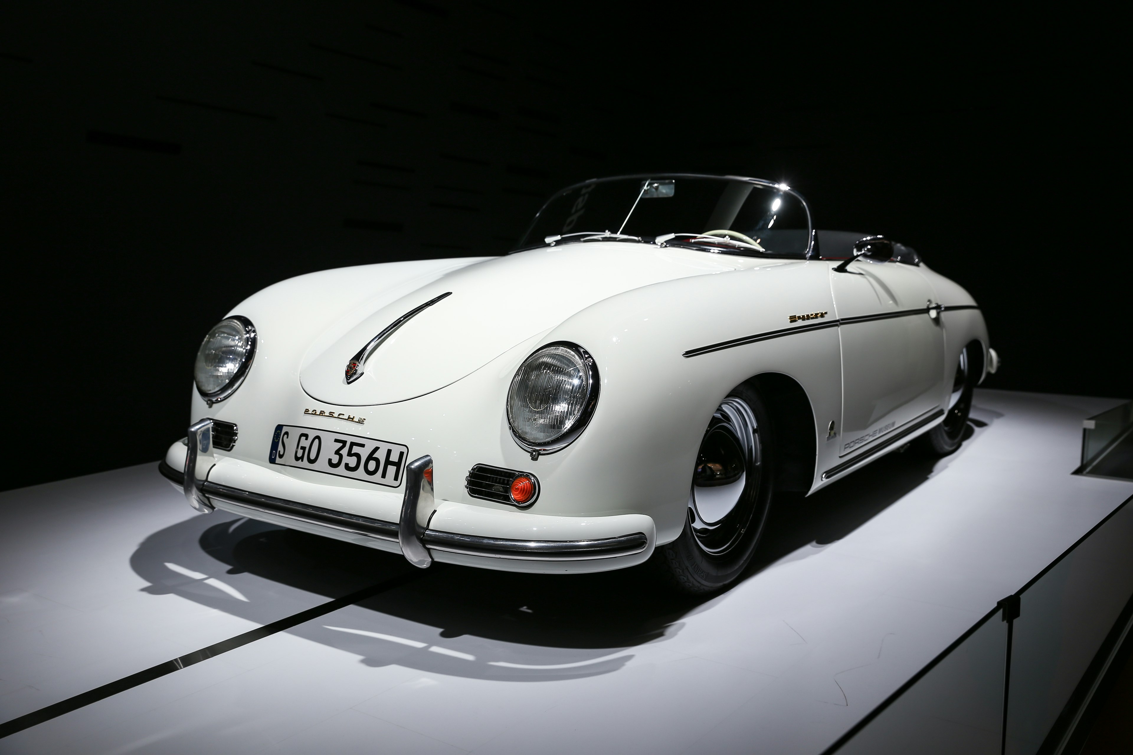 Weißer Porsche 356A Cabriolet vor dunklem Hintergrund ausgestellt