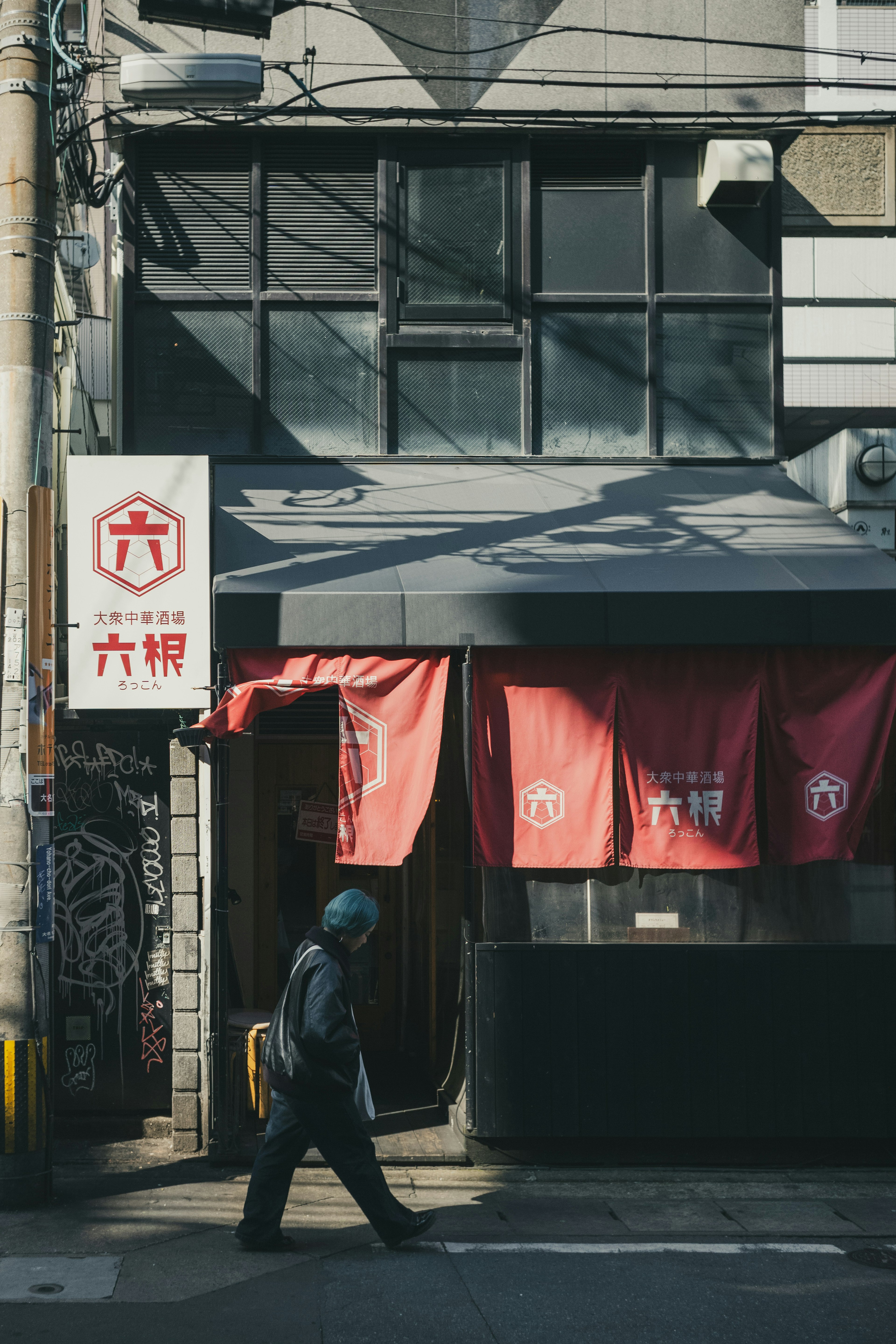 赤い暖簾がかかる日本の飲食店の外観と通行人