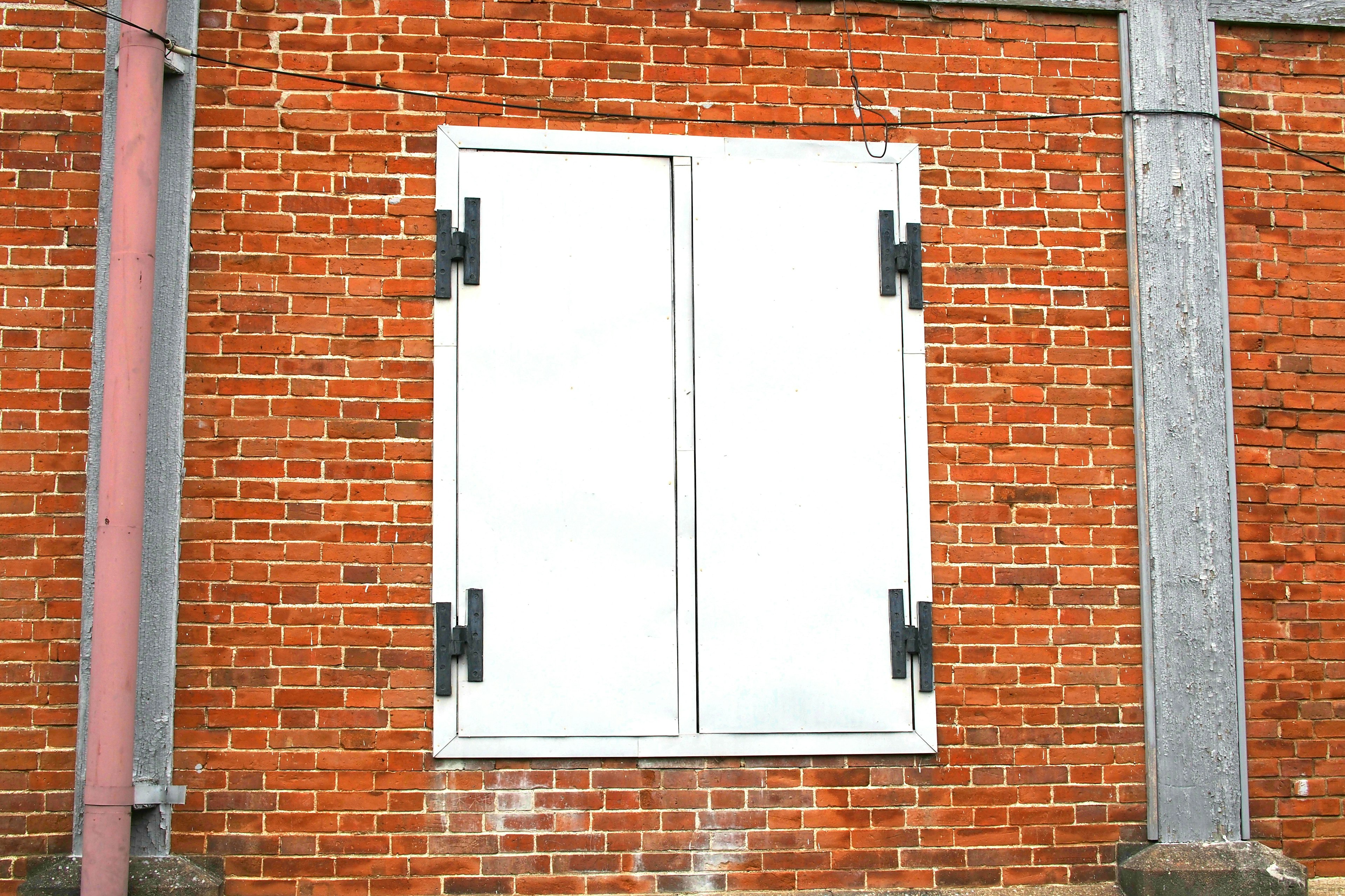 Image de volets blancs sur un mur en briques rouges