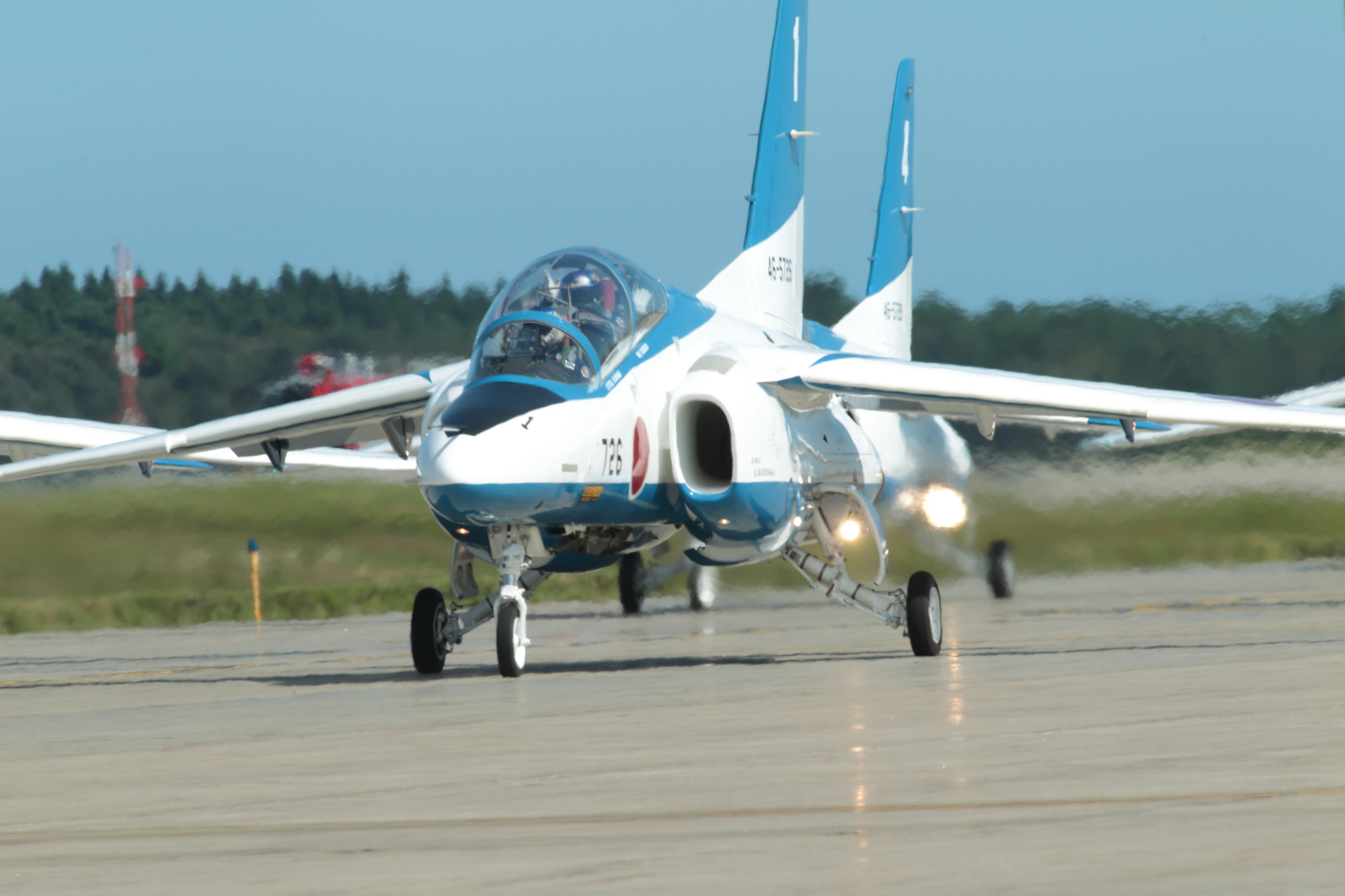 A blue and white painted fighter jet taxiing on the runway