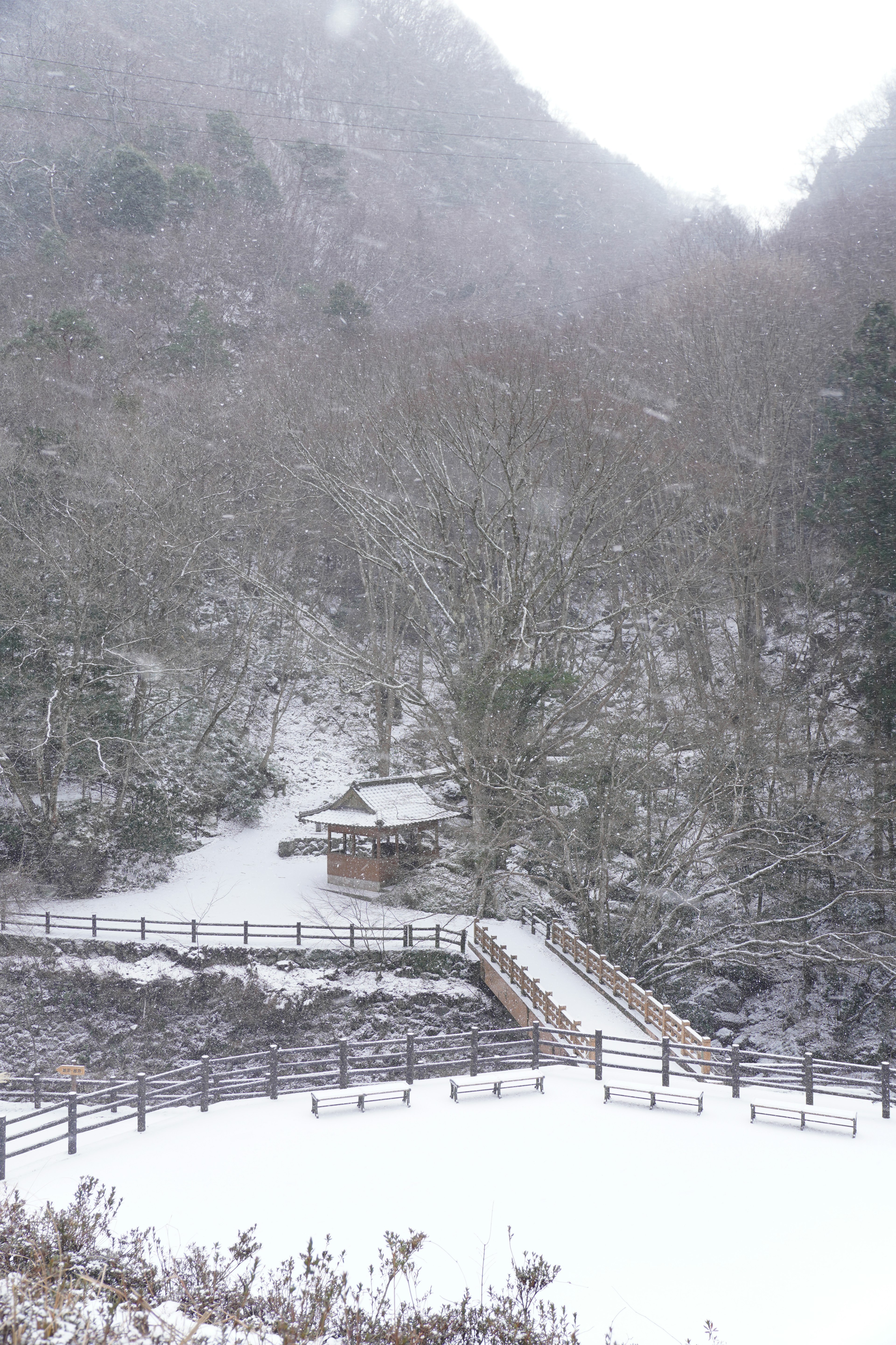 Schneebedeckte Landschaft mit einer Hütte und einer Brücke