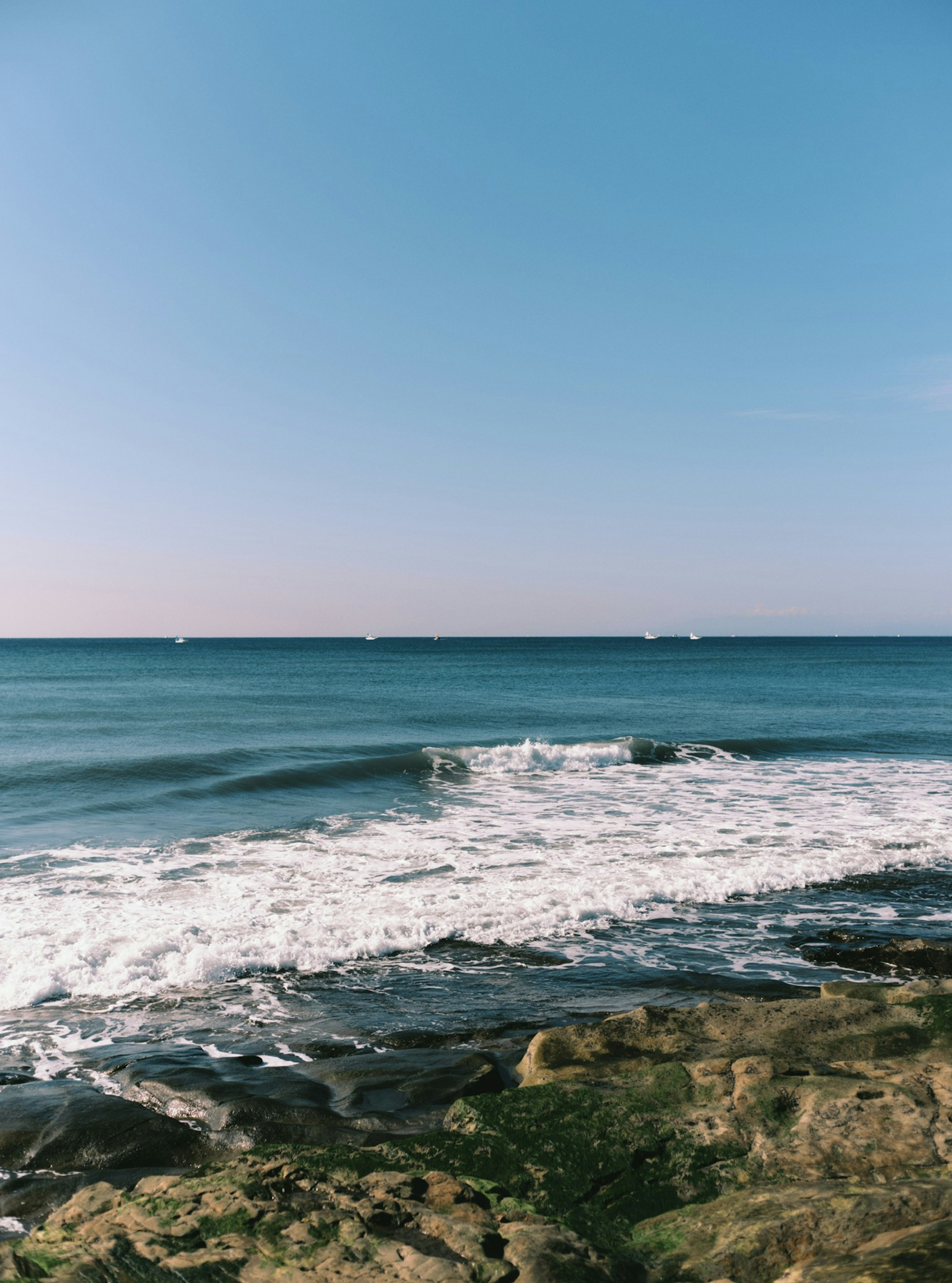 Pemandangan pantai dengan lautan biru dan ombak yang menghantam