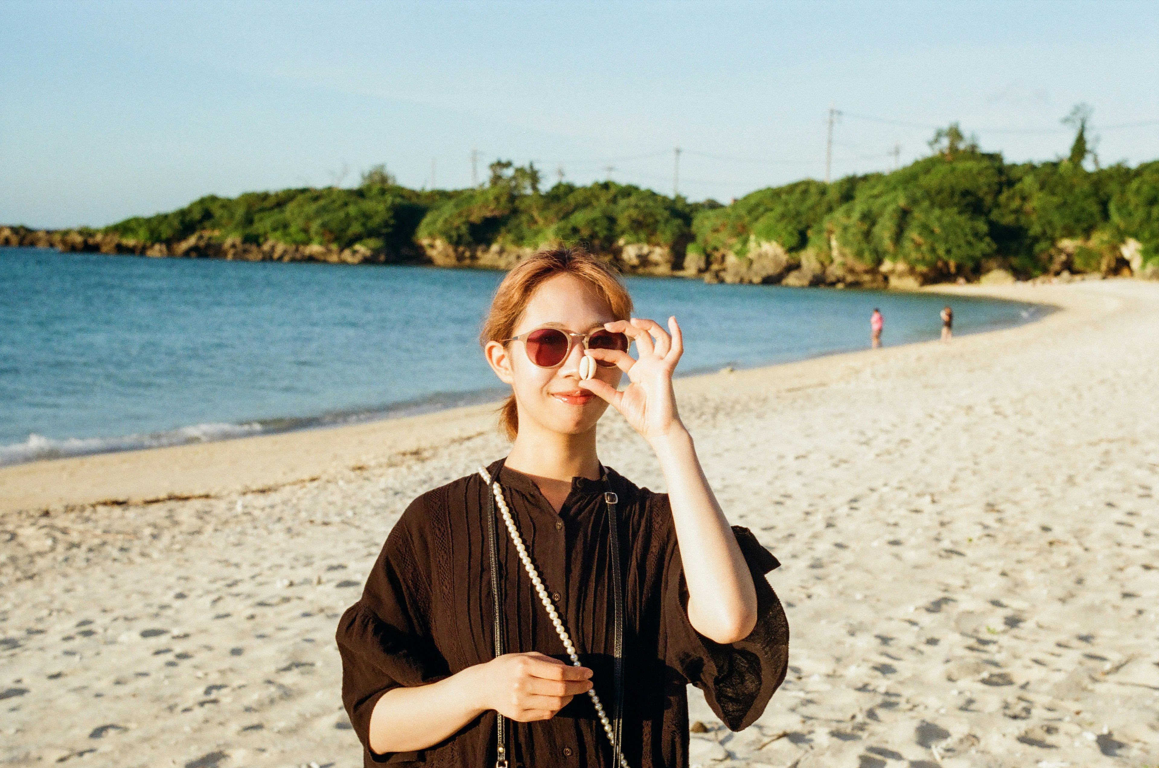 Una donna con occhiali da sole che posa sulla spiaggia